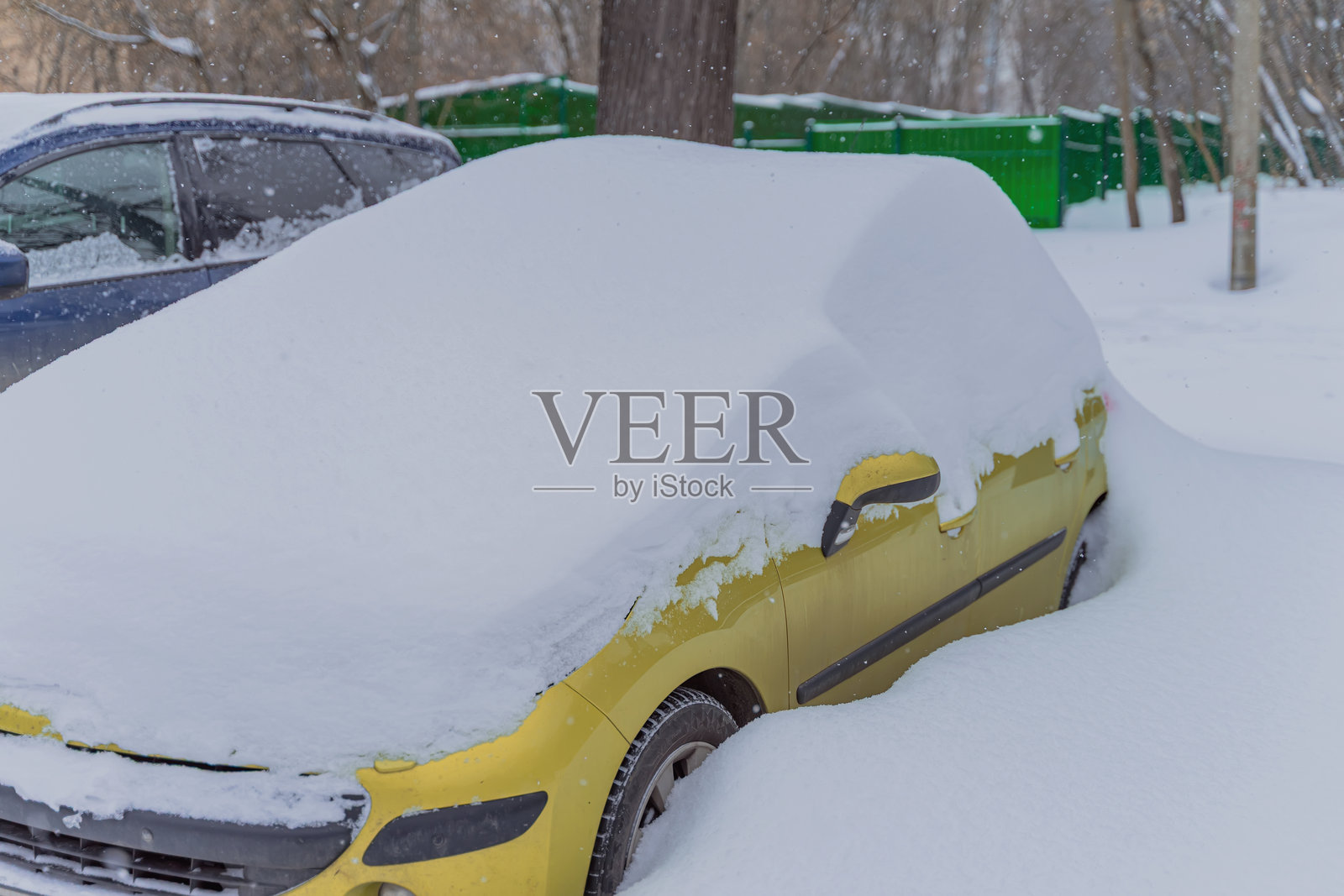 冬季暴风雪过后，城市被大雪覆盖。一辆黄色汽车被困在居民区的深雪中，这是暴风雪期间的景象。体现了极端天气、城市基础设施瘫痪以及全球变暖的影响的概念。照片摄影图片