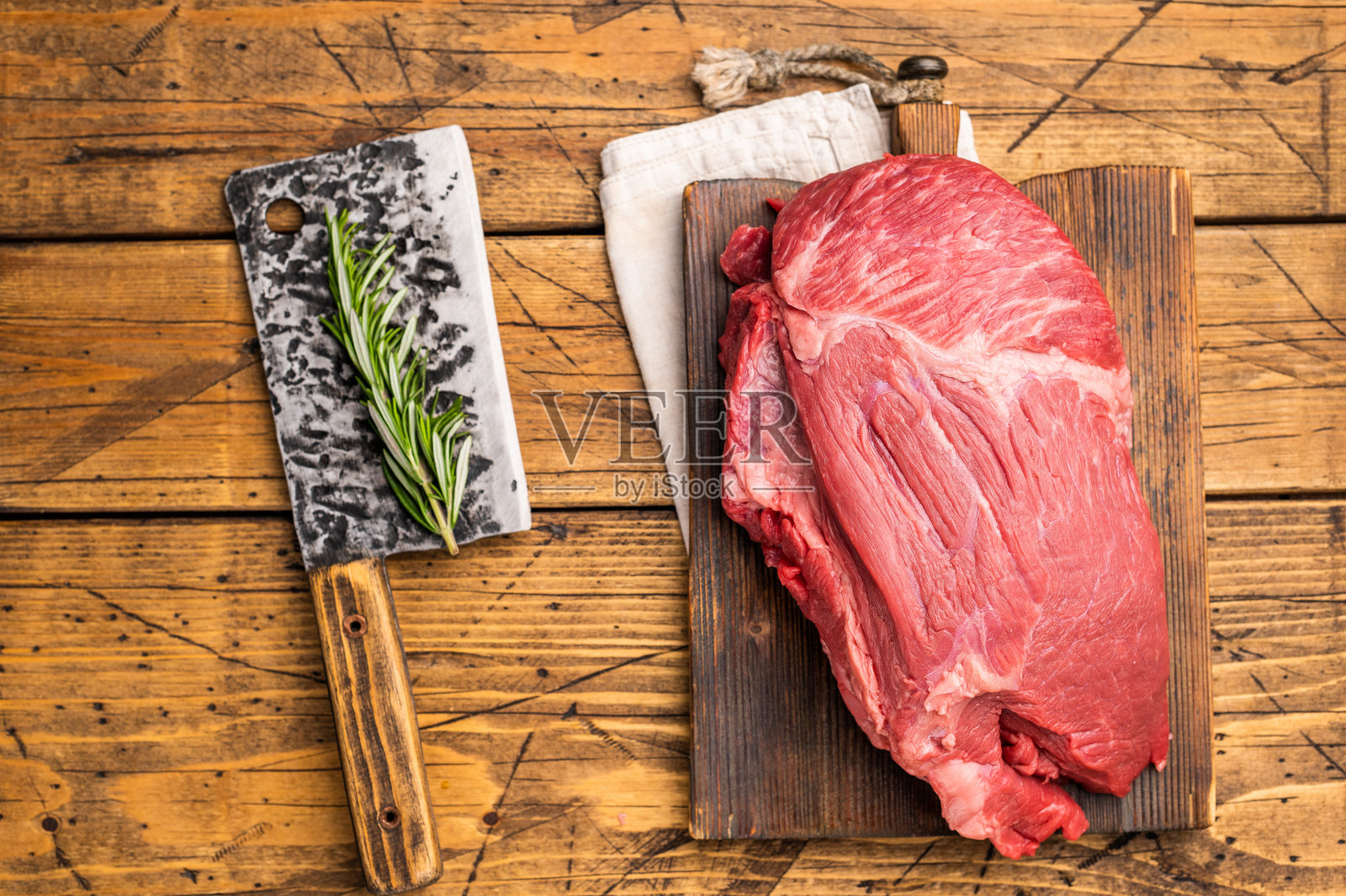 新鲜的生圆牛后腿肉，内侧圆肉，配香草用于烤制。木质背景。俯视。照片摄影图片
