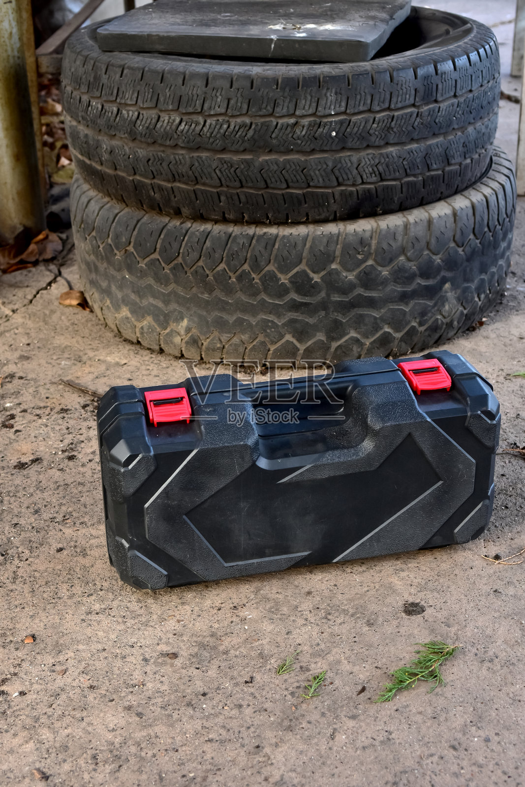 车库或工作室环境中的黑色塑料工具箱，放置在堆叠的汽车轮胎附近，用于维修和保养照片摄影图片