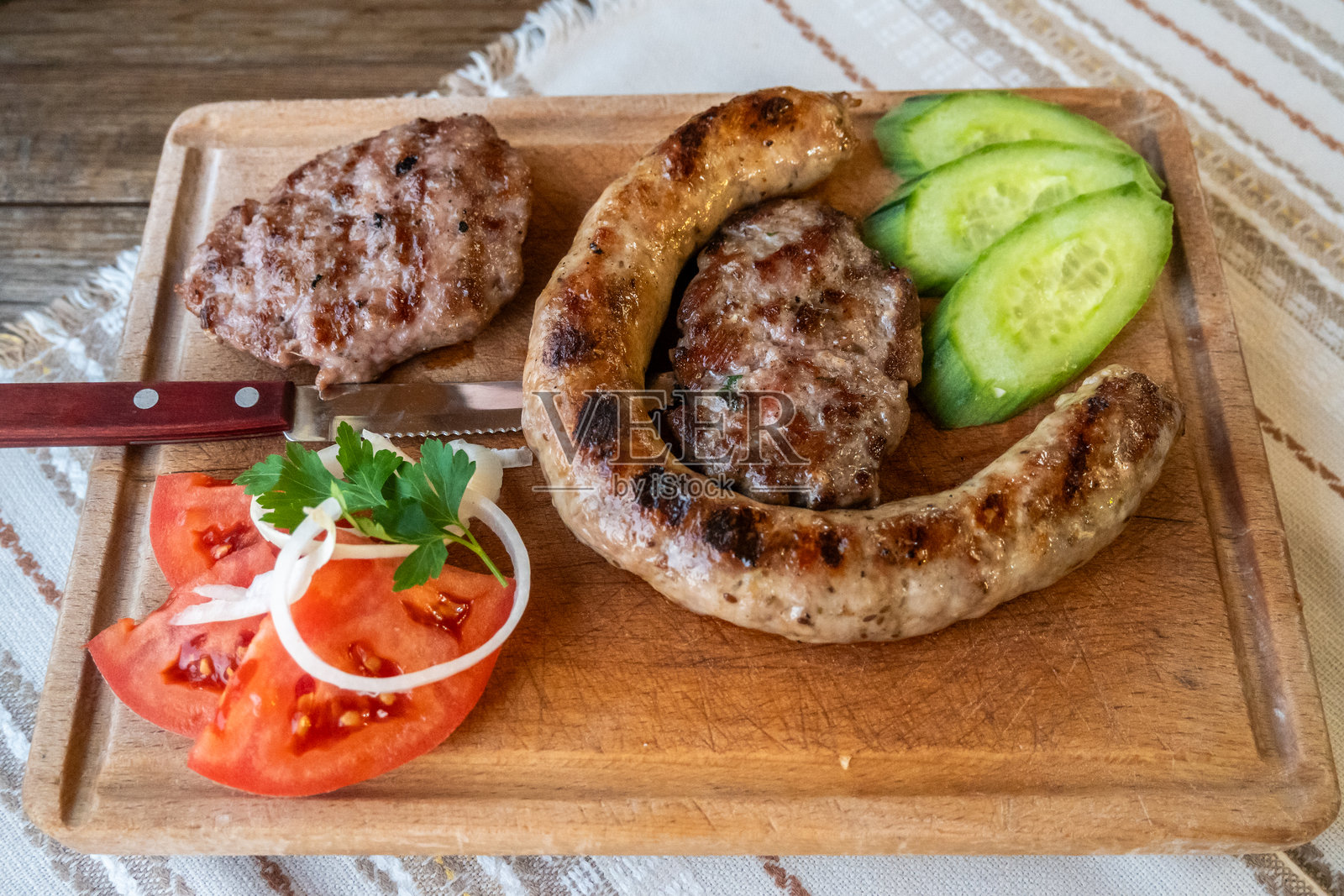 木板上丰盛的烤肉拼盘配新鲜蔬菜照片摄影图片