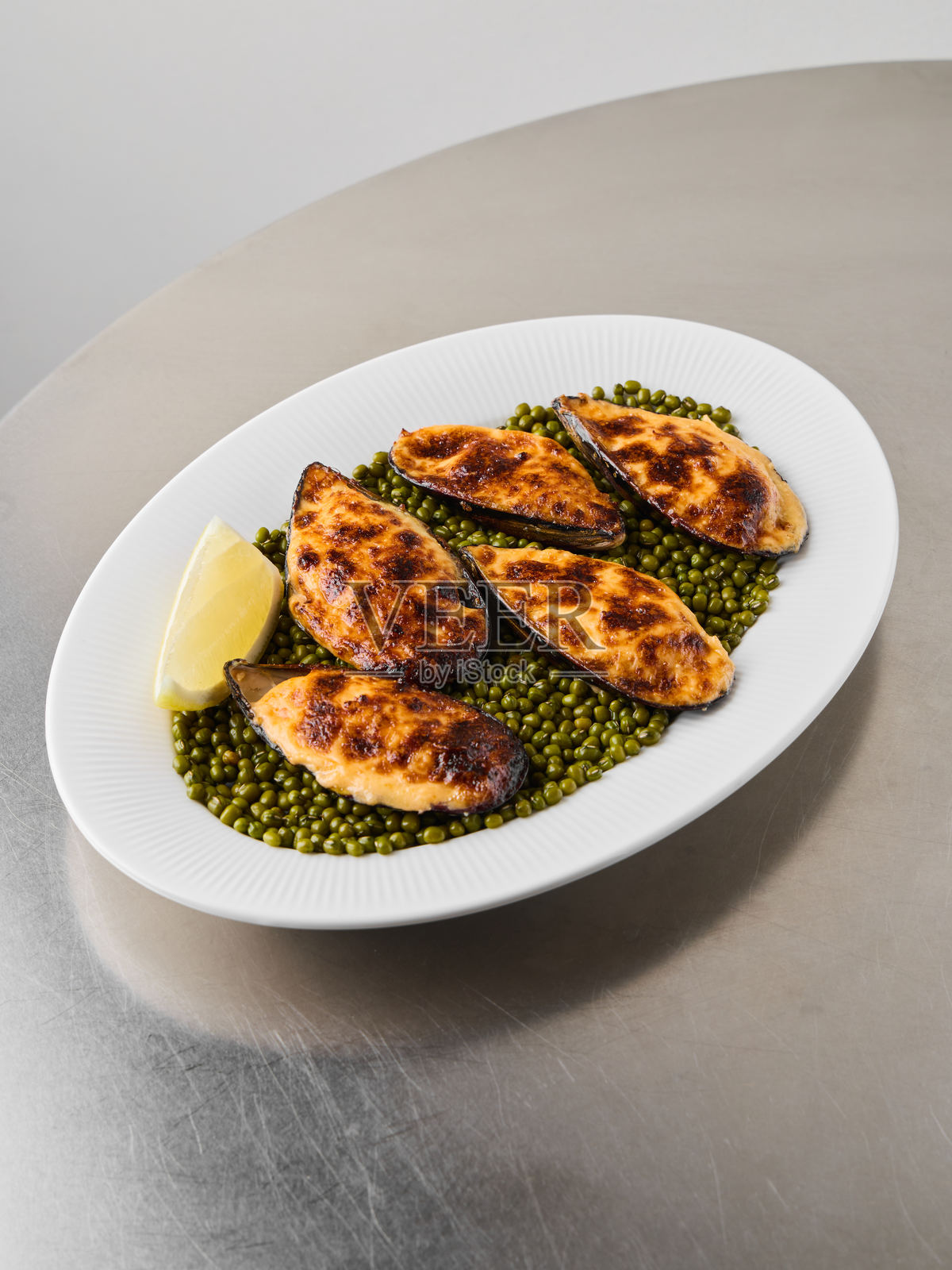 精致烘烤的贻贝，配以新鲜豌豆和酥脆面包屑照片摄影图片