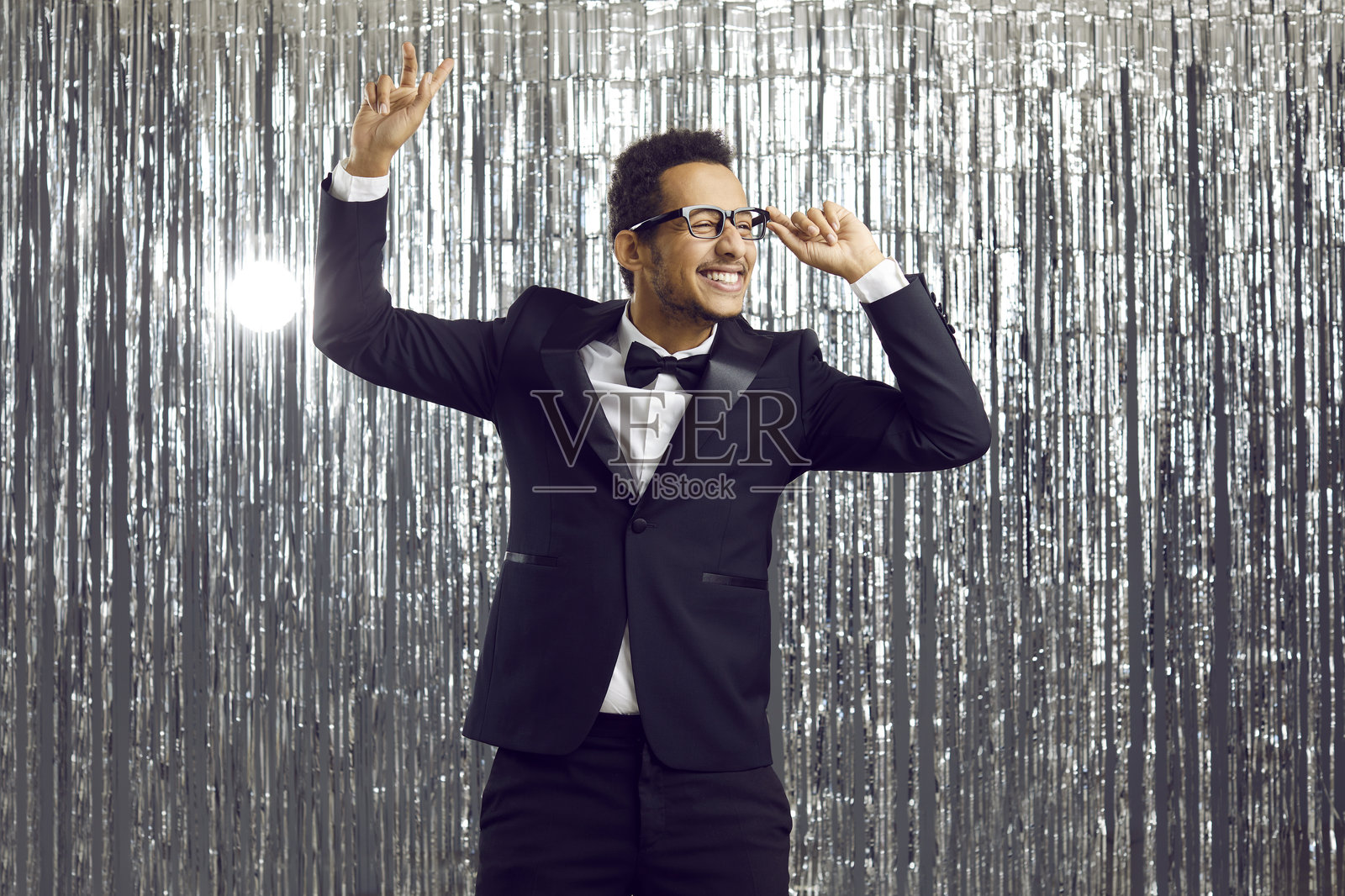 穿着燕尾服的快乐有趣的年轻少数族裔男子在迪斯科派对上跳舞，玩得很开心照片摄影图片