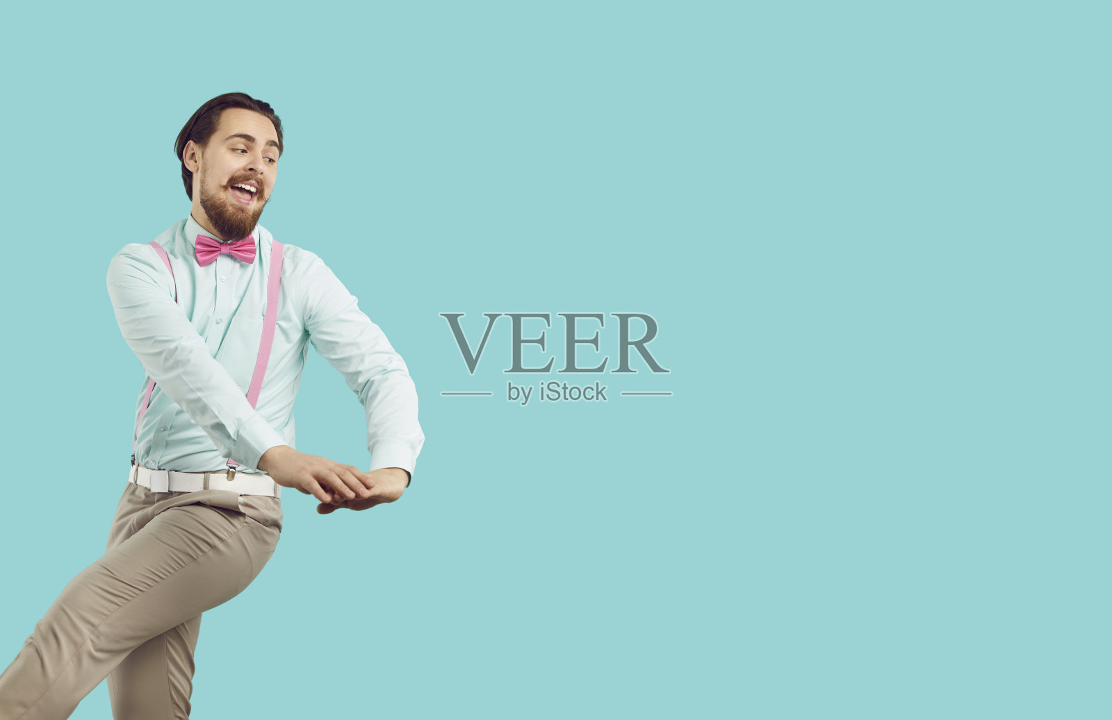 快乐、时髦、有型的留胡子潮男，在浅蓝色背景上玩得很开心。照片摄影图片