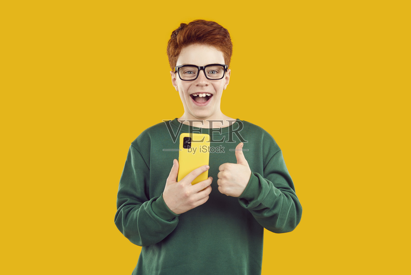 红发少年用智能手机竖起大拇指照片摄影图片