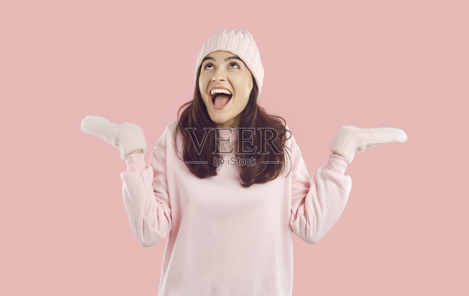 戴着手套的快乐兴奋的女人，在捕捉雪花时惊叹于冬天。照片摄影图片