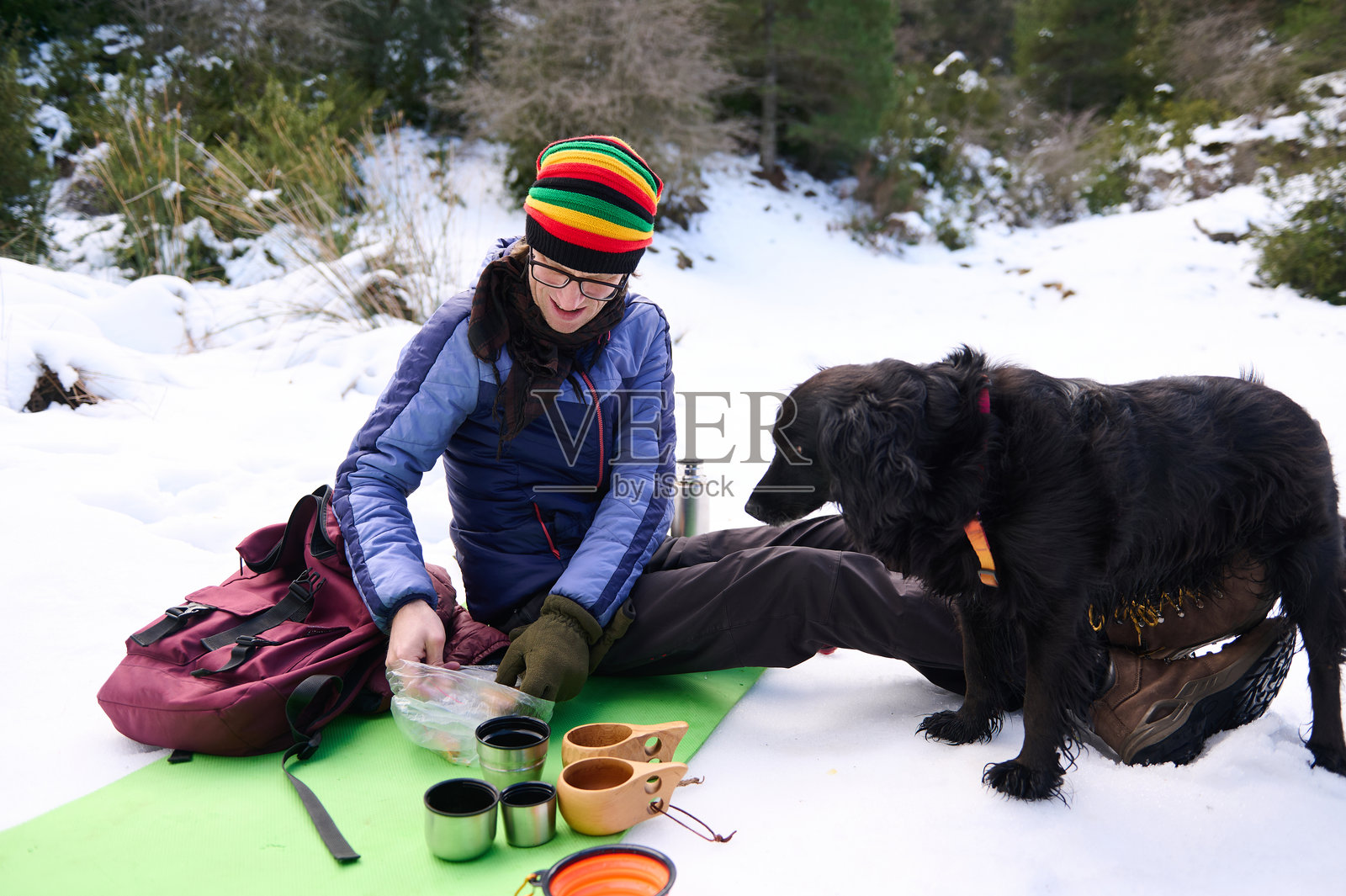 女人在山地营地享受雪地冬日探险：与狗狗共进咖啡时光照片摄影图片