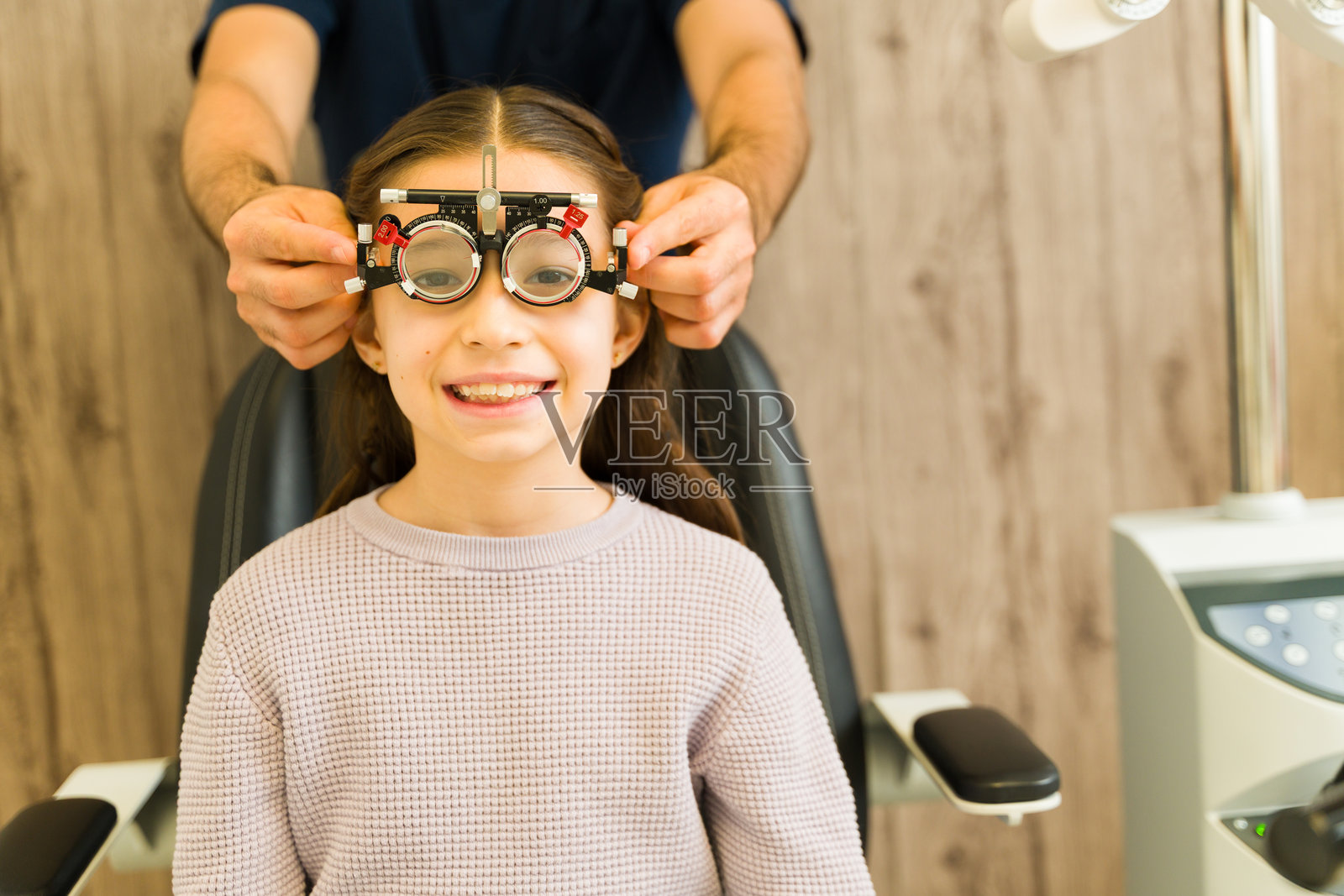 眼科医生为小女孩准备视力检查，年轻的患者在视光诊所的视力测试中微笑照片摄影图片
