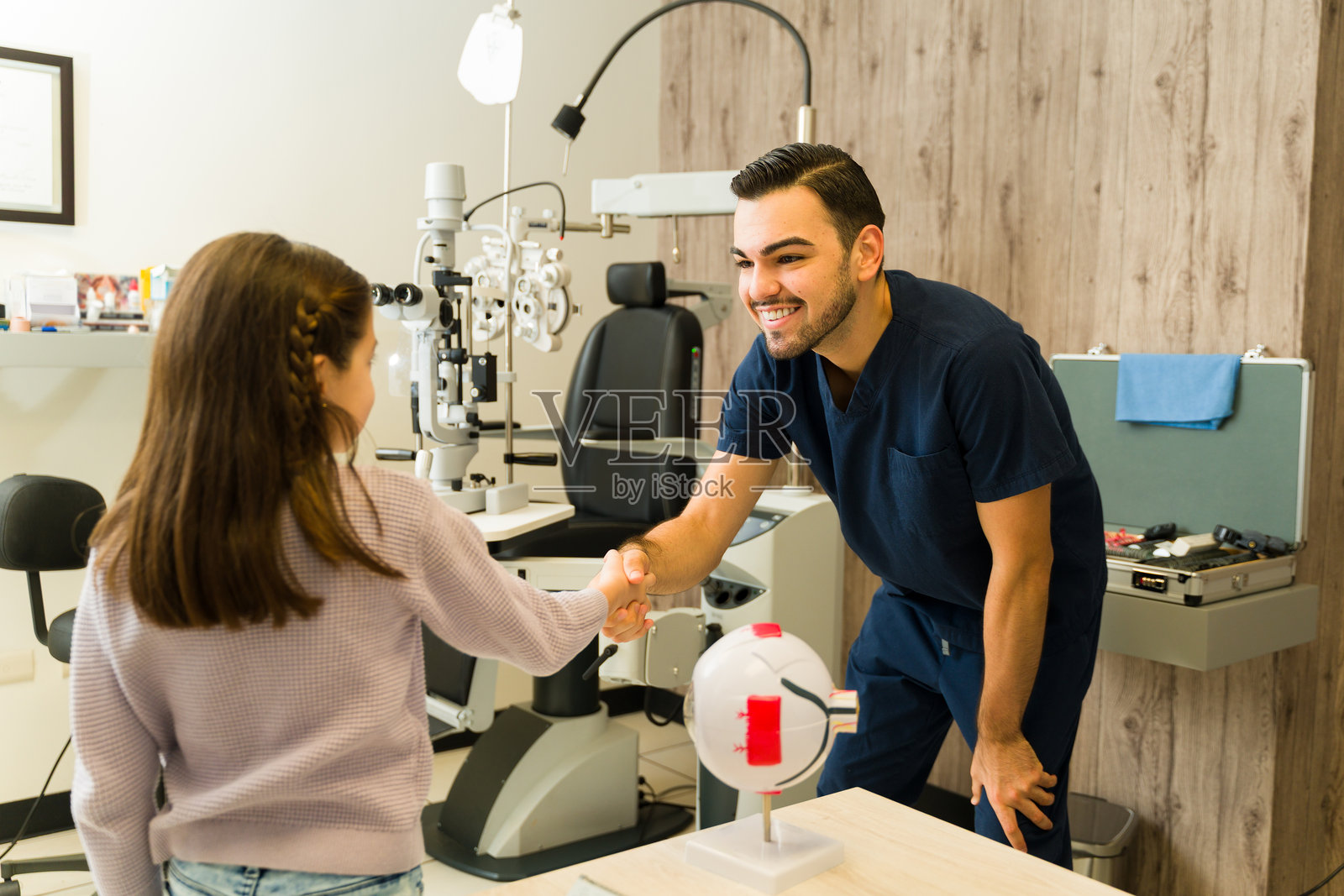 眼科医生与儿童患者握手，营造友好氛围，确保儿童眼科检查和视力健康照片摄影图片
