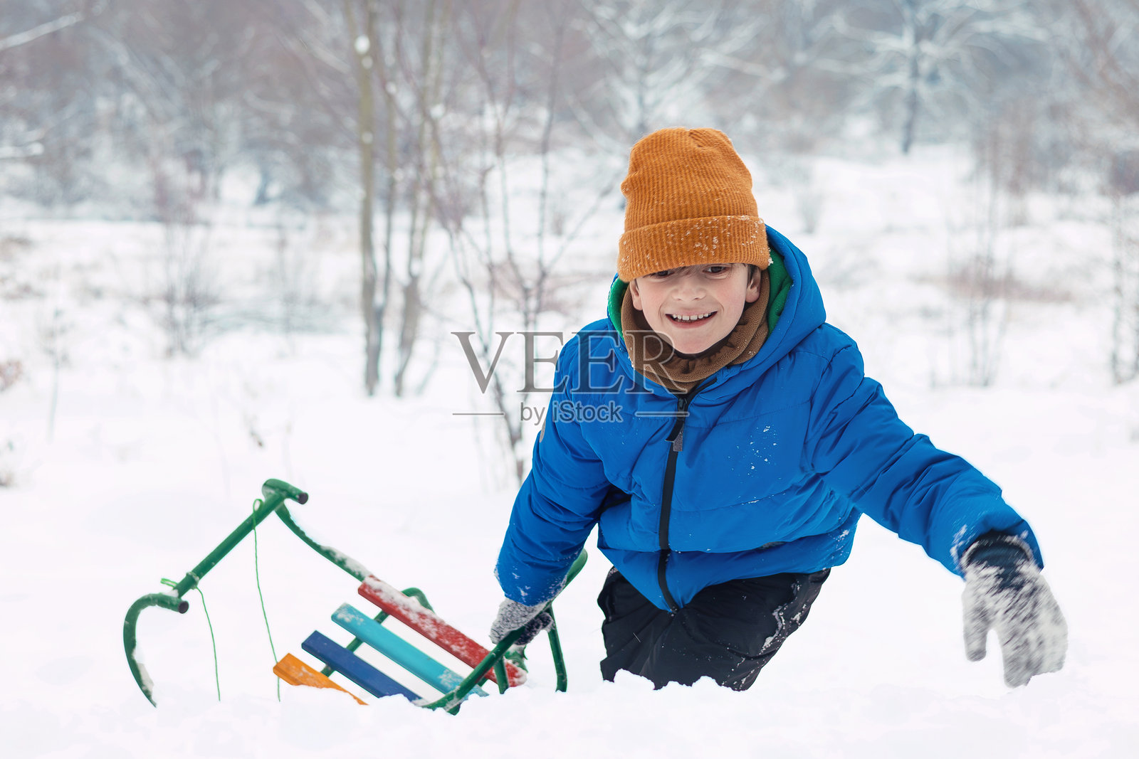 雪地冬景中玩雪橇的男孩照片摄影图片