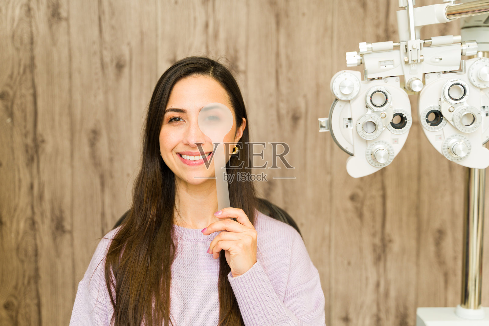 患者在验光预约中，使用遮眼器遮盖一只眼睛进行视力检查照片摄影图片