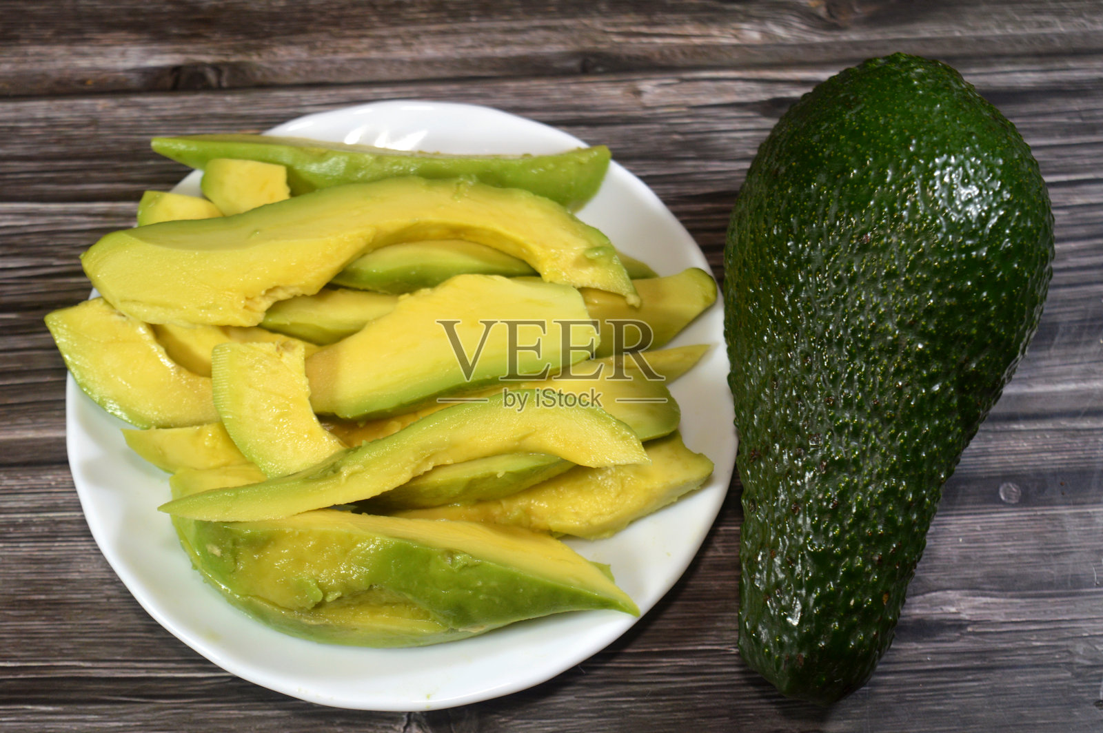 牛油果切片，一种营养丰富的果实，植物学上属于大浆果，以其奶油般的质地、健康的单不饱和脂肪和纤维而闻名照片摄影图片