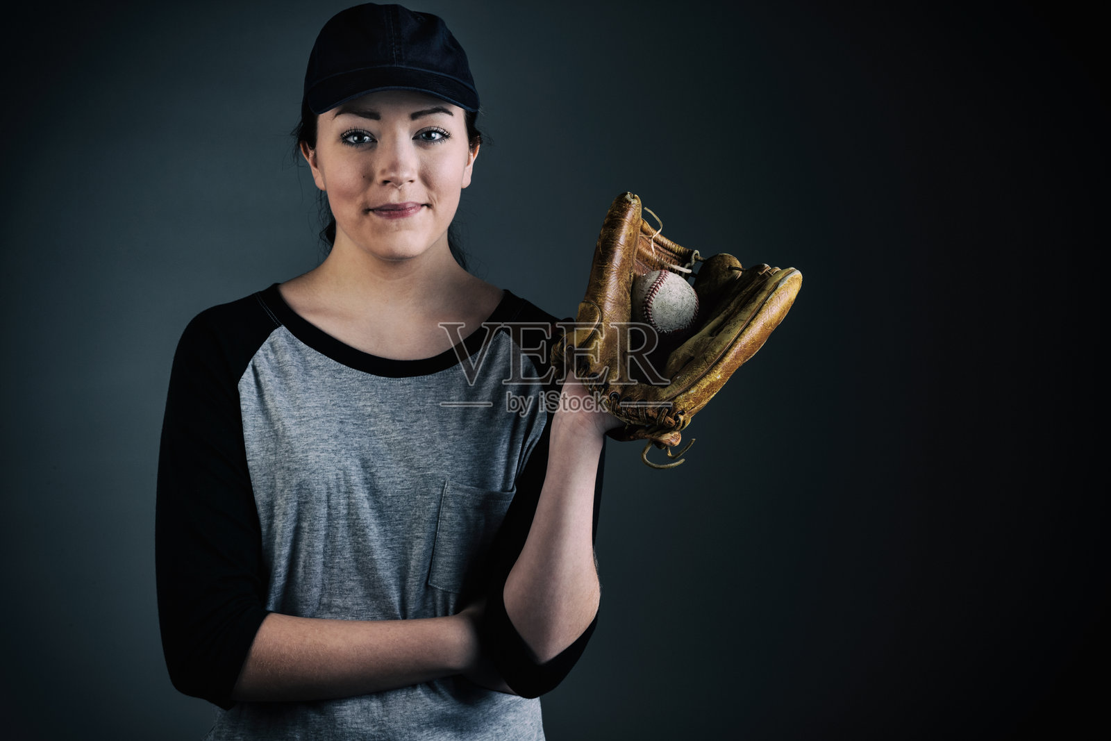 戴着棒球手套、帽子和T恤的少女照片摄影图片