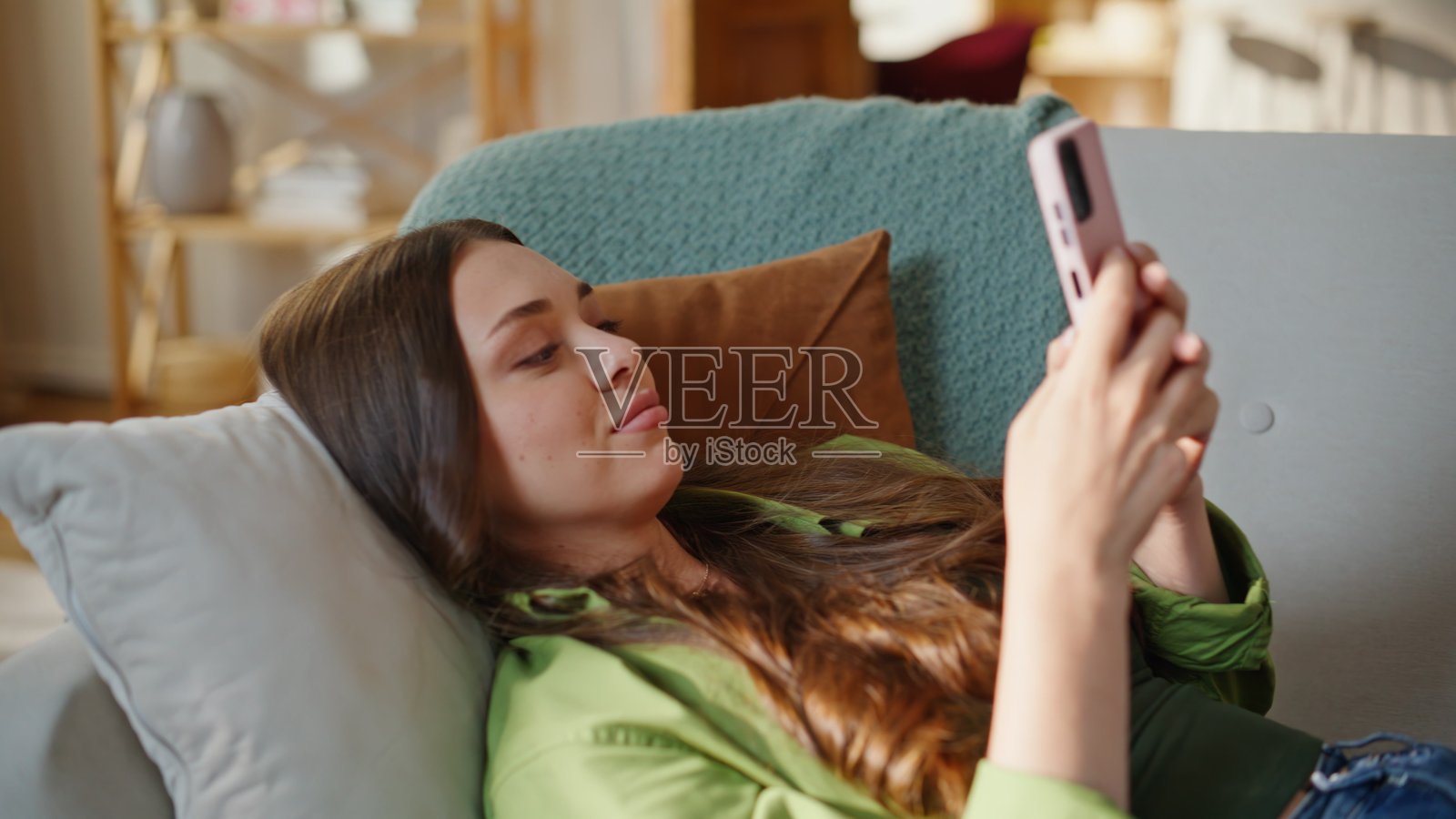 舒服地躺在沙发上用手机发消息，特写观看媒体内容照片摄影图片