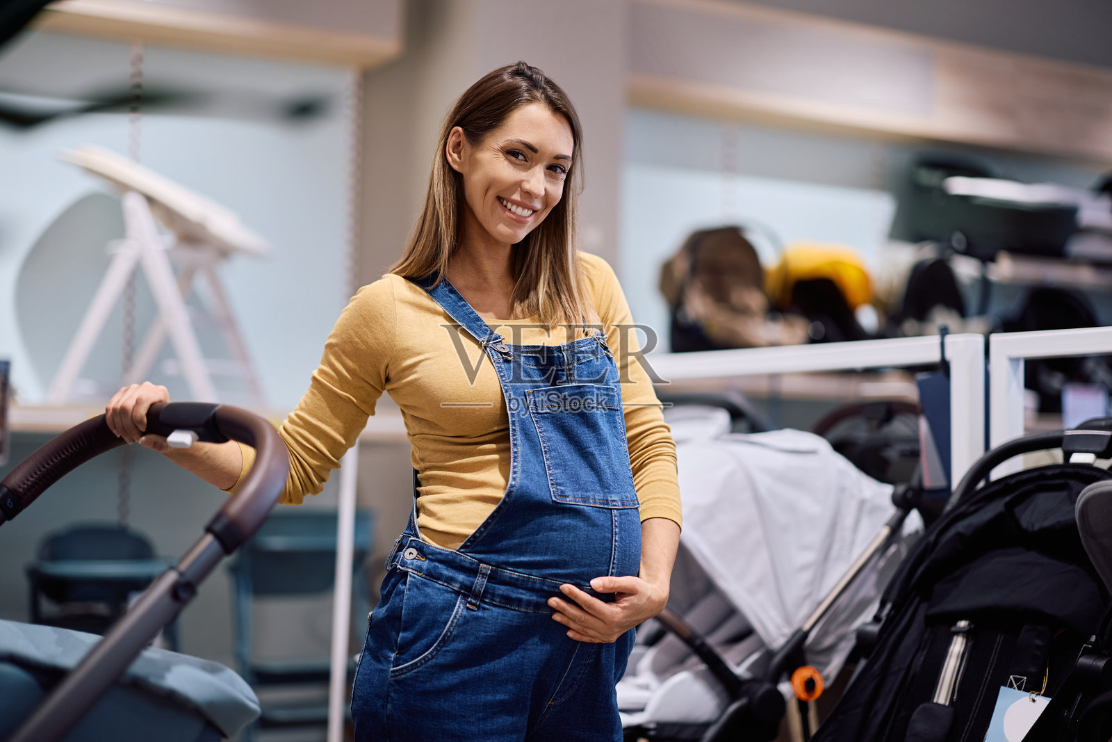 快乐的孕妇在推着婴儿车购物，并看向镜头照片摄影图片