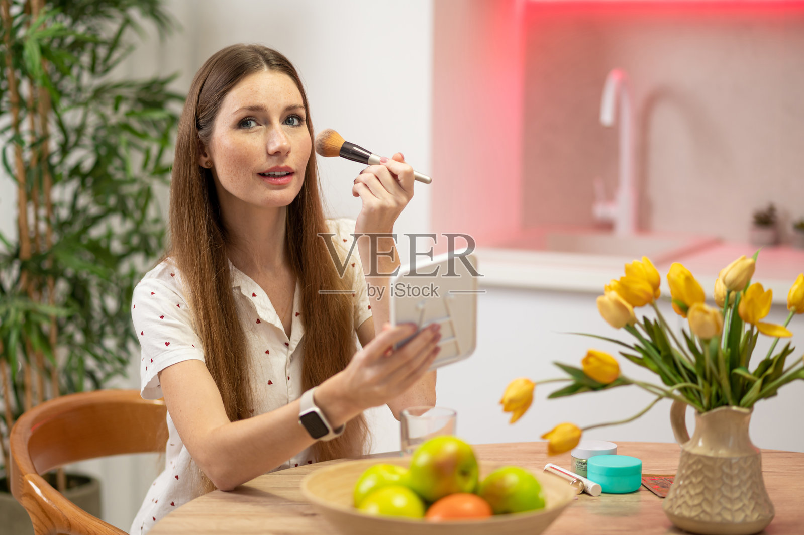 留着长发的年轻美女坐在桌前，手中拿着化妆刷照片摄影图片