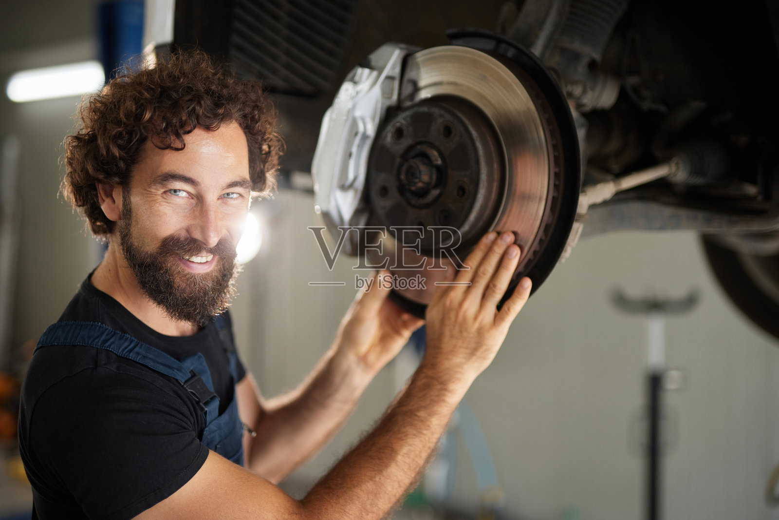 微笑的汽车修理师在汽车修理店检查刹车盘照片摄影图片