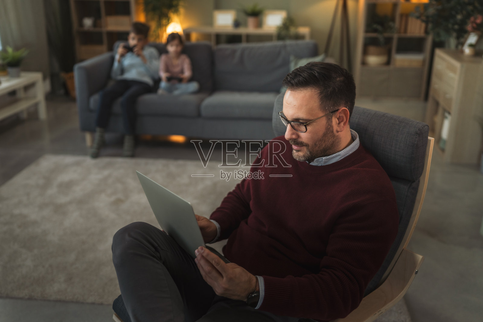 父亲在家使用笔记本电脑工作，孩子们在旁边照片摄影图片