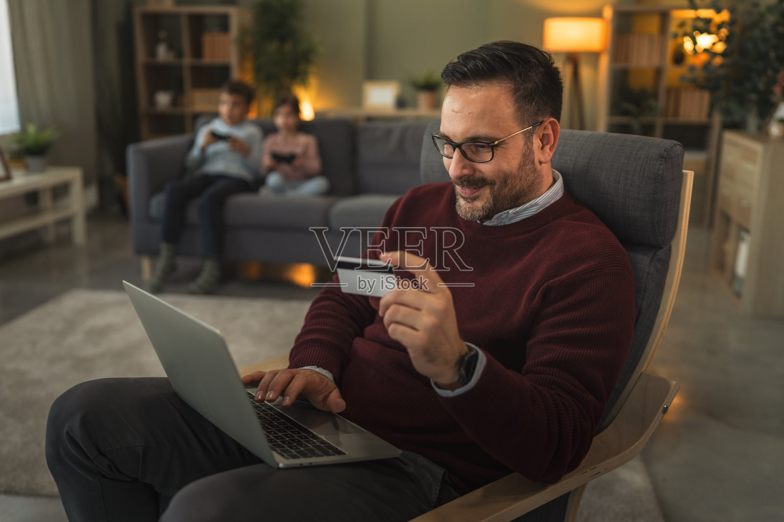 父亲在家使用笔记本电脑，并用信用卡进行在线购物照片摄影图片