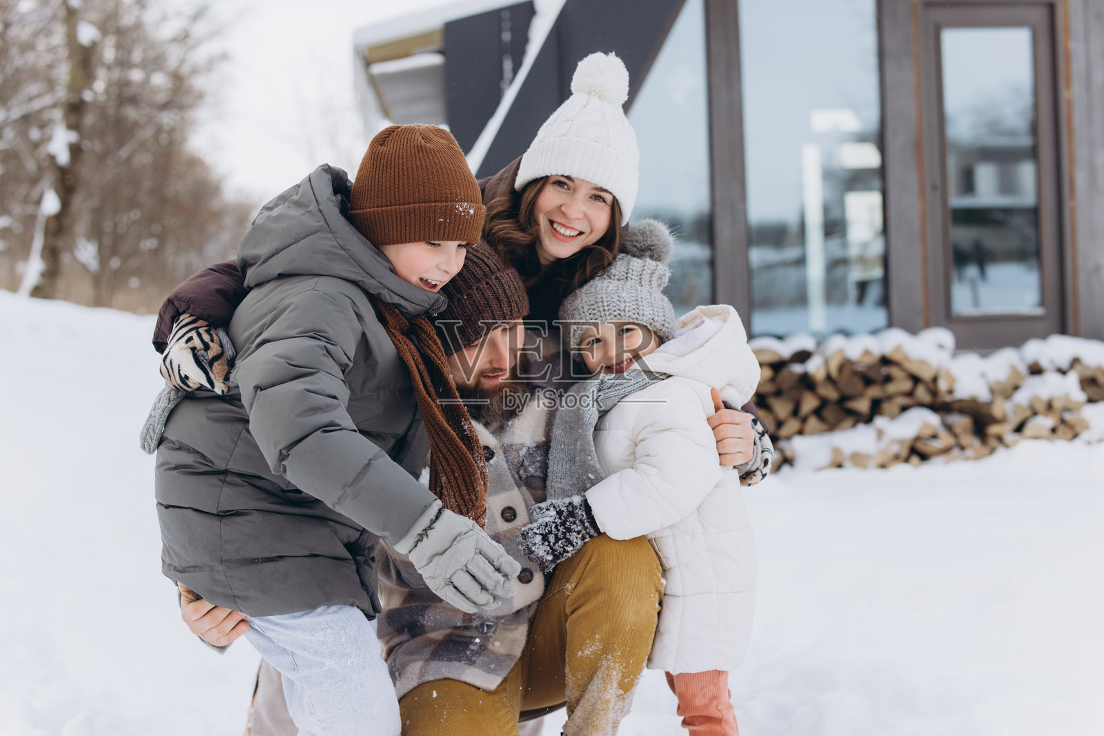 寒假期间，幸福的一家人在雪中拥抱照片摄影图片