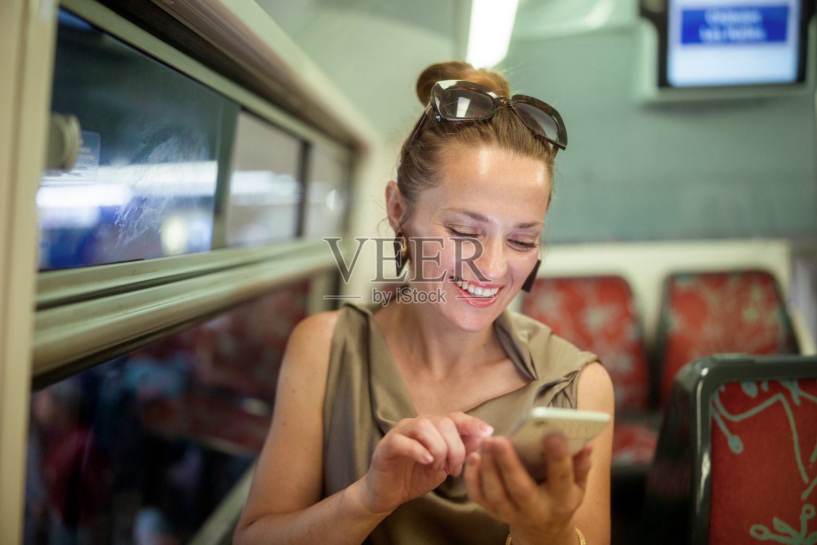 火车旅途中，一位快乐的女士正在浏览智能手机照片摄影图片