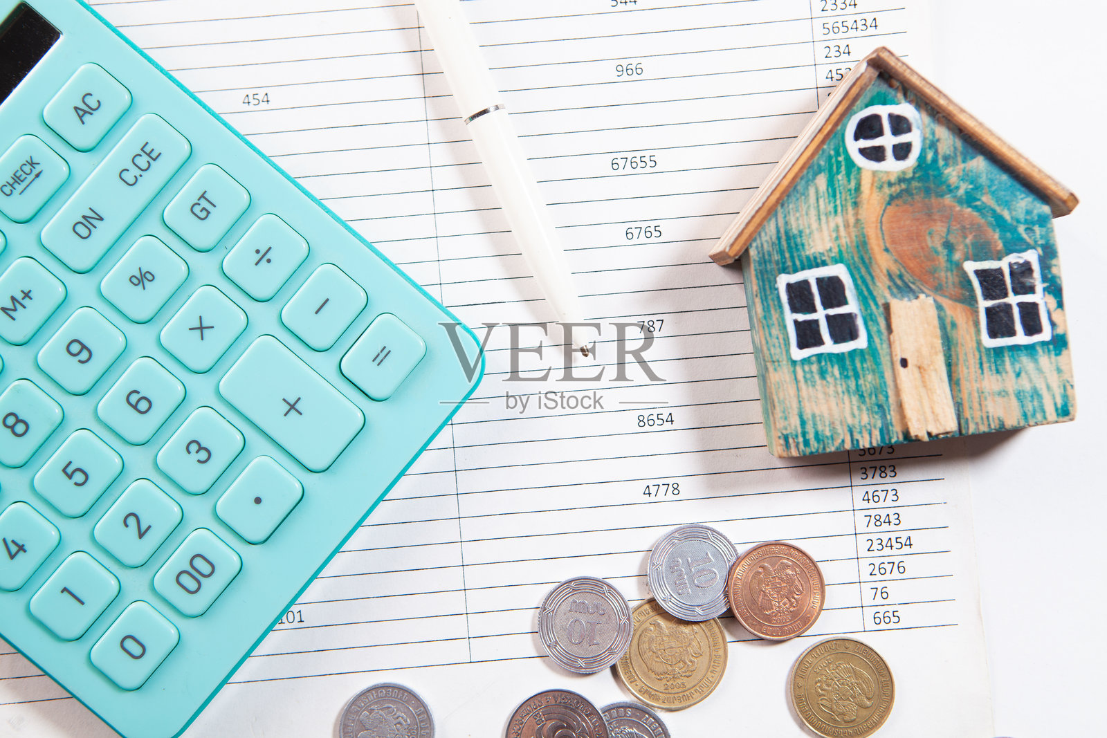 白色背景上的房屋计算器和硬币照片摄影图片