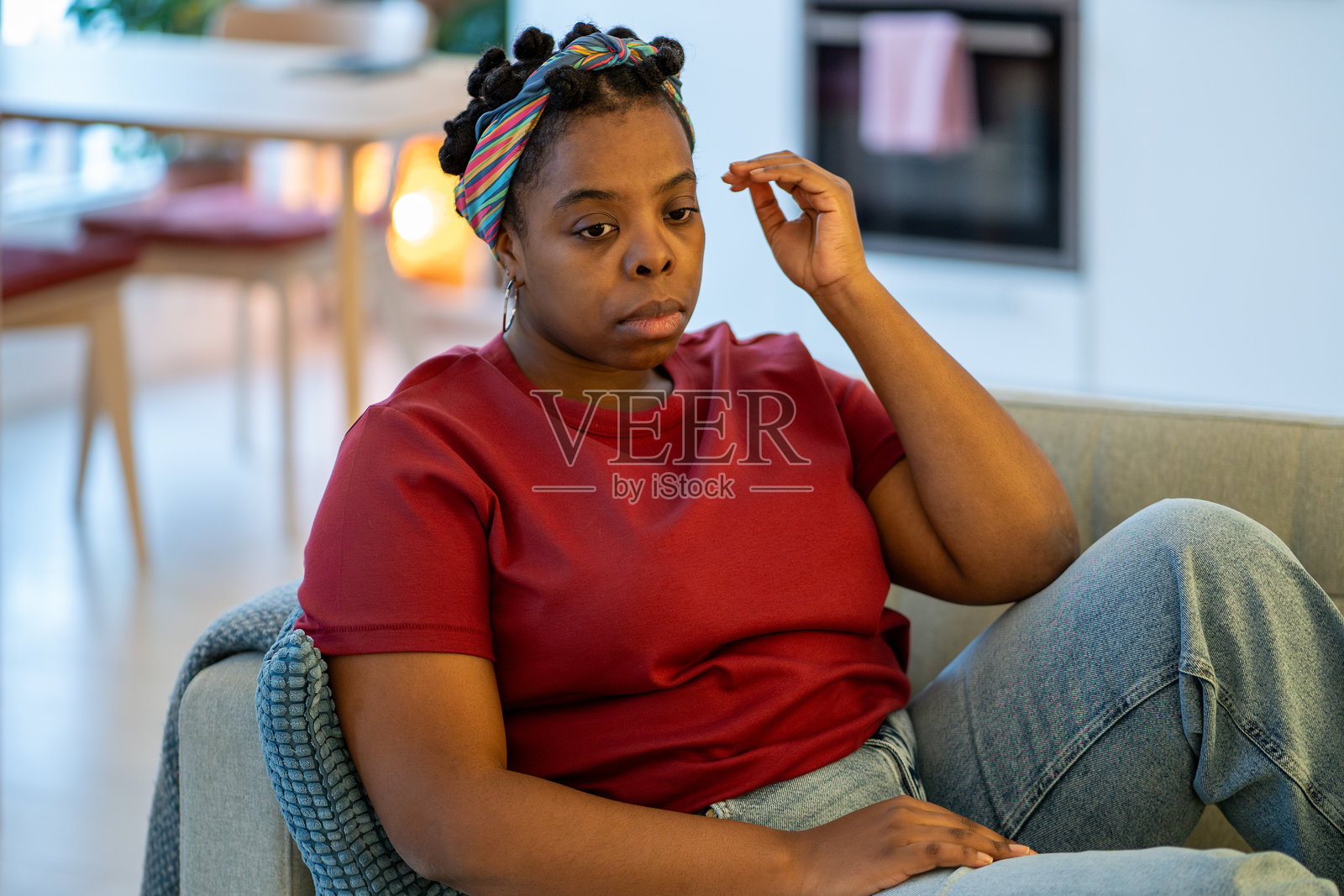生活艰难时期，忧郁的黑人女性沉思地坐在家里的沙发上，被担忧和焦虑压垮。照片摄影图片