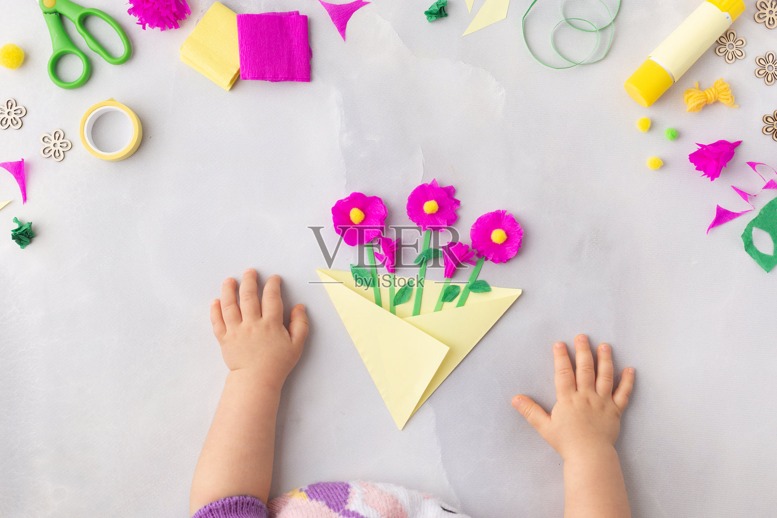 简单的纸艺花朵手工，适合儿童。包含手部特写。适用于母亲节、生日等场合。照片摄影图片