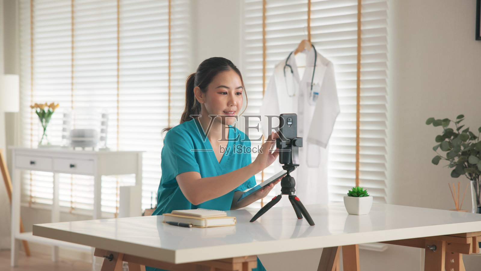 年轻亚裔女性，Z世代，抗衰老专家，现代护士，进行在线直播，准备拍摄手机App视频自拍，提供心理健康护理，作为数字虚拟副业，亚洲网红正在拍摄。照片摄影图片