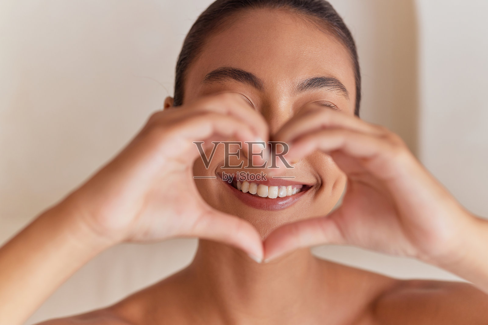 微笑的女性用双手比心，强调口腔健康照片摄影图片