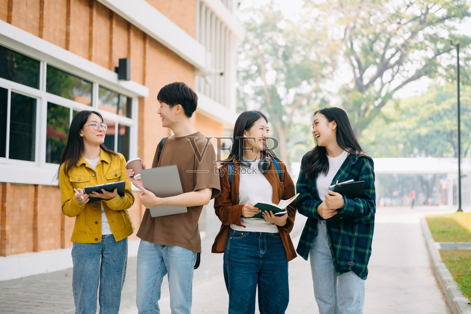 年轻的大学生们在校园公园的草地上放松地坐着看书照片摄影图片