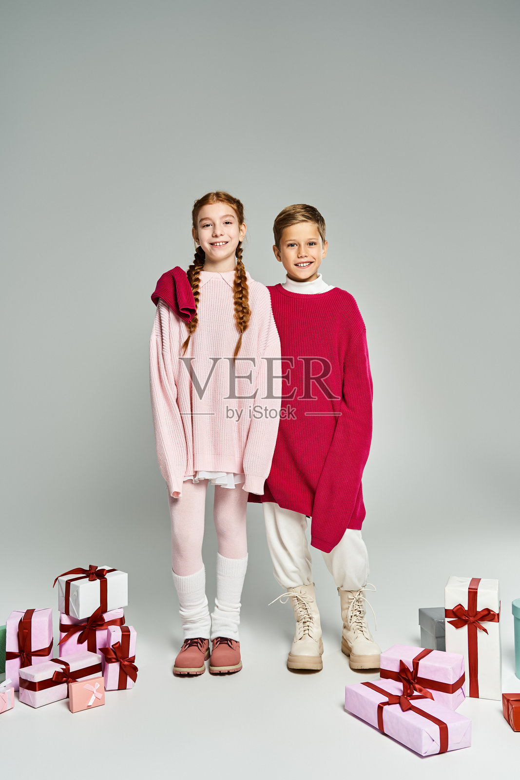 喜悦的兄妹俩穿着舒适的冬季毛衣，手捧礼物，正为节日庆典做准备照片摄影图片