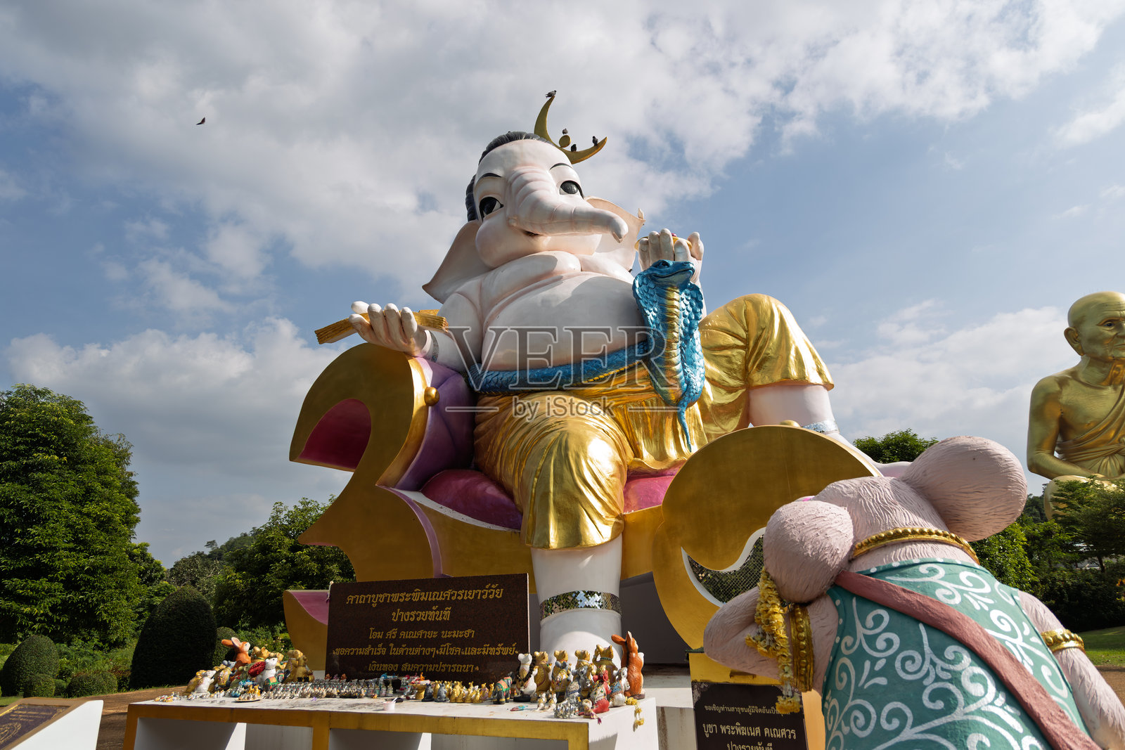 泰国考艾龙普托寺公园内，一尊巨大的金色象头神甘尼许雕像坐落于户外，旁边还有一只老鼠塑像。照片摄影图片