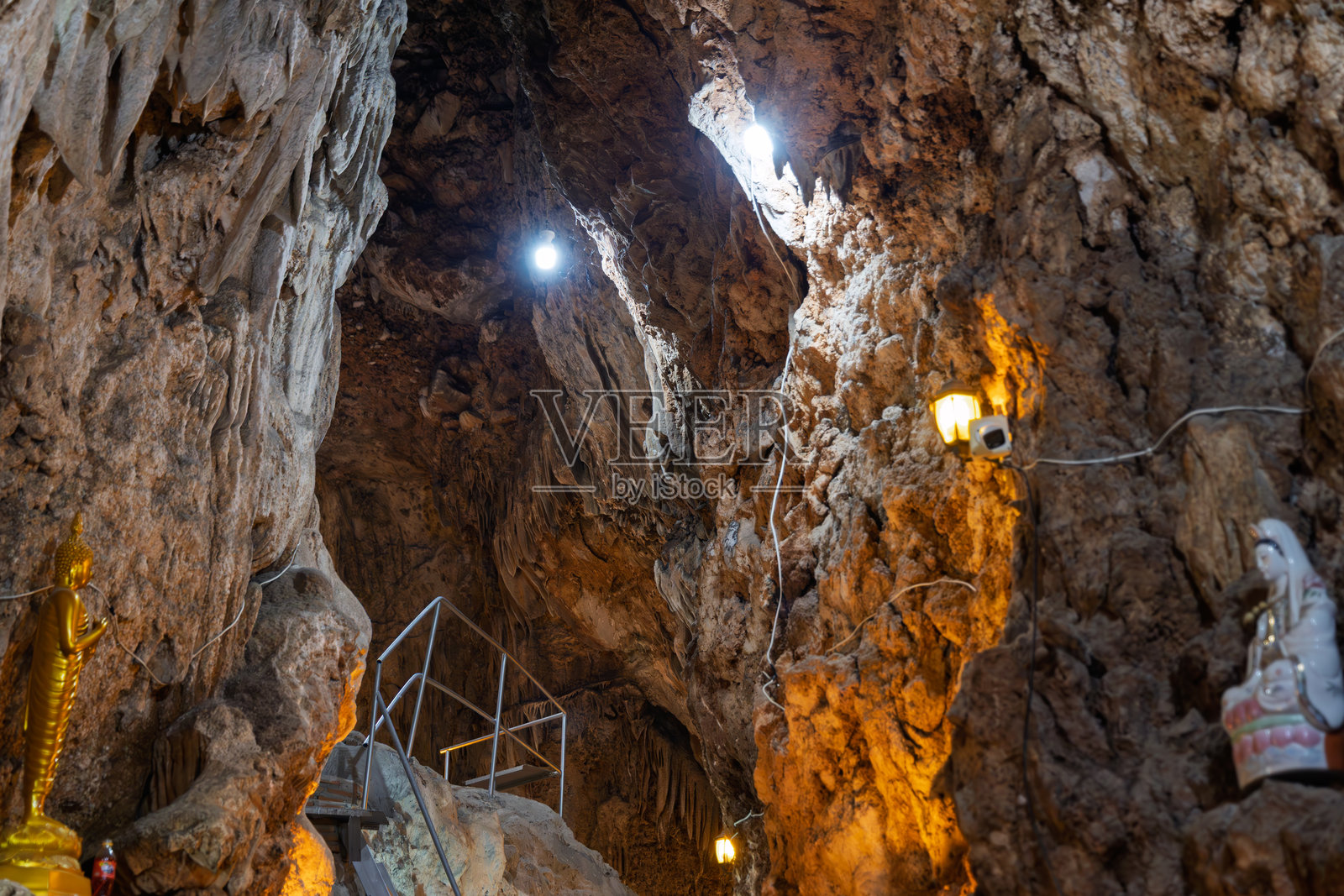 泰国考艾国家公园的天然洞穴神龛，内有金色佛像和白色神祇雕像，在温暖灯光的照耀下照片摄影图片