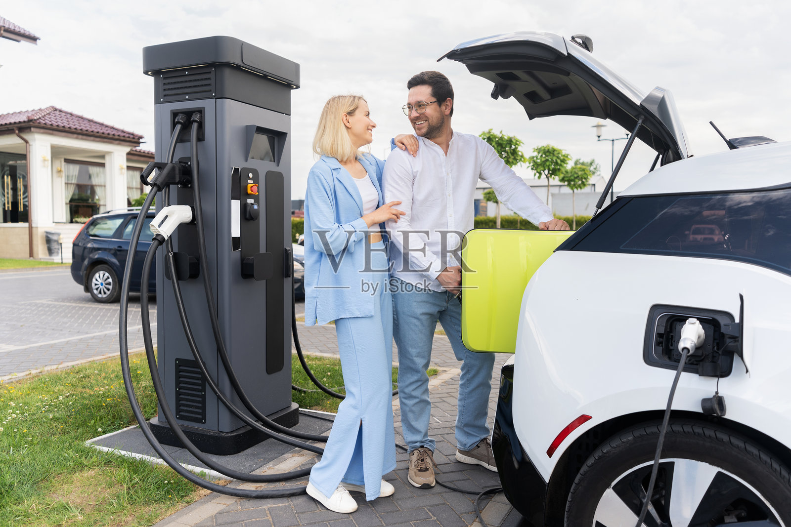 一对快乐的夫妇在户外公共充电站为电动汽车充电照片摄影图片