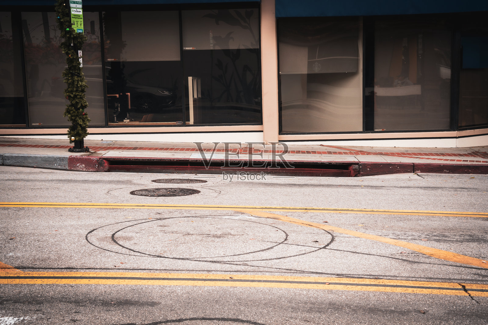 建筑物附近有轮胎印和井盖的城市街道景象照片摄影图片