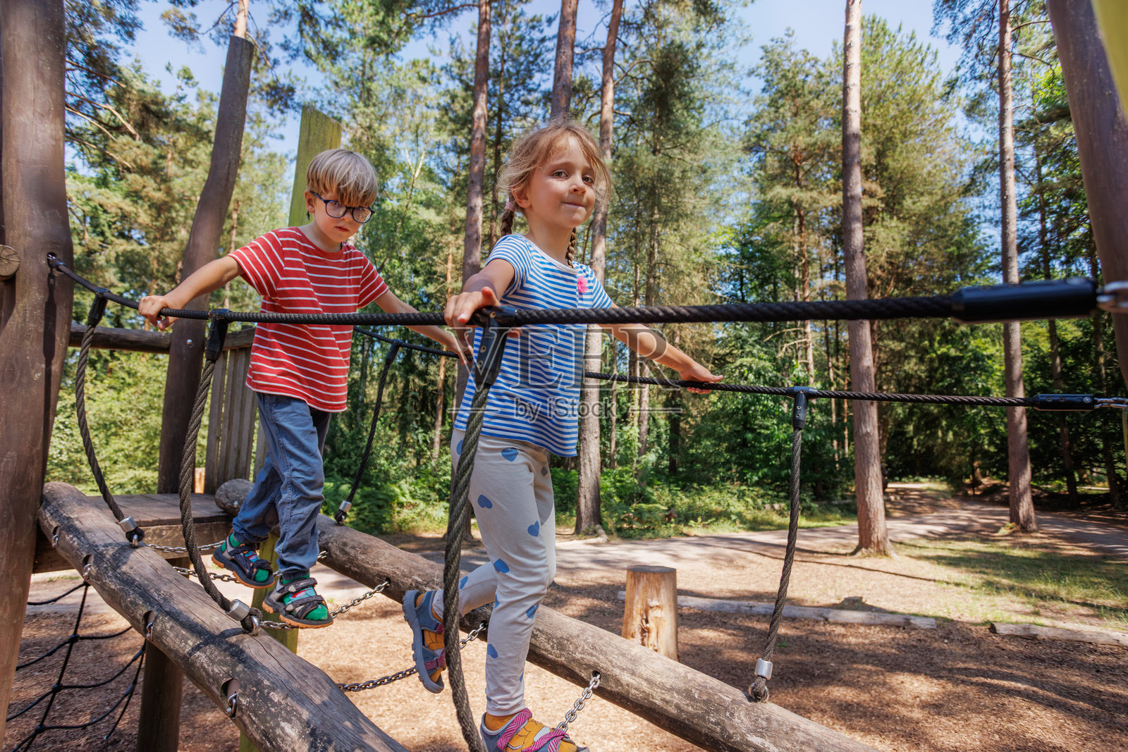 夏令营里，孩子们在森林公园的绳网上攀爬照片摄影图片