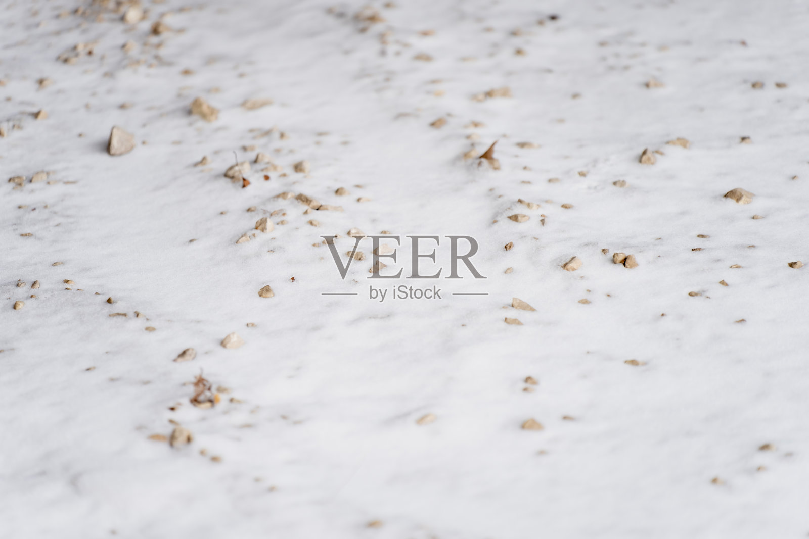 雪覆盖的地面，散布着小石子和砾石，构成适合用作背景的自然冬季纹理，展现了极简的户外环境细节照片摄影图片