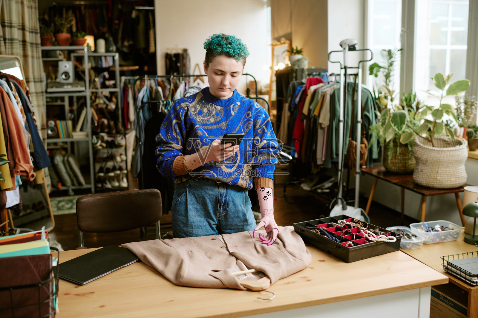 年轻女子在复古商店用假肢为二手衣定价照片摄影图片