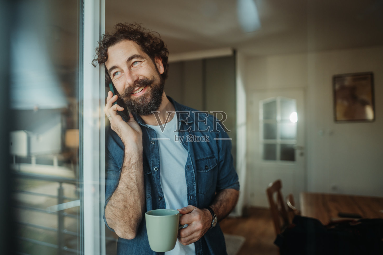 男人在家一边喝咖啡一边打电话照片摄影图片