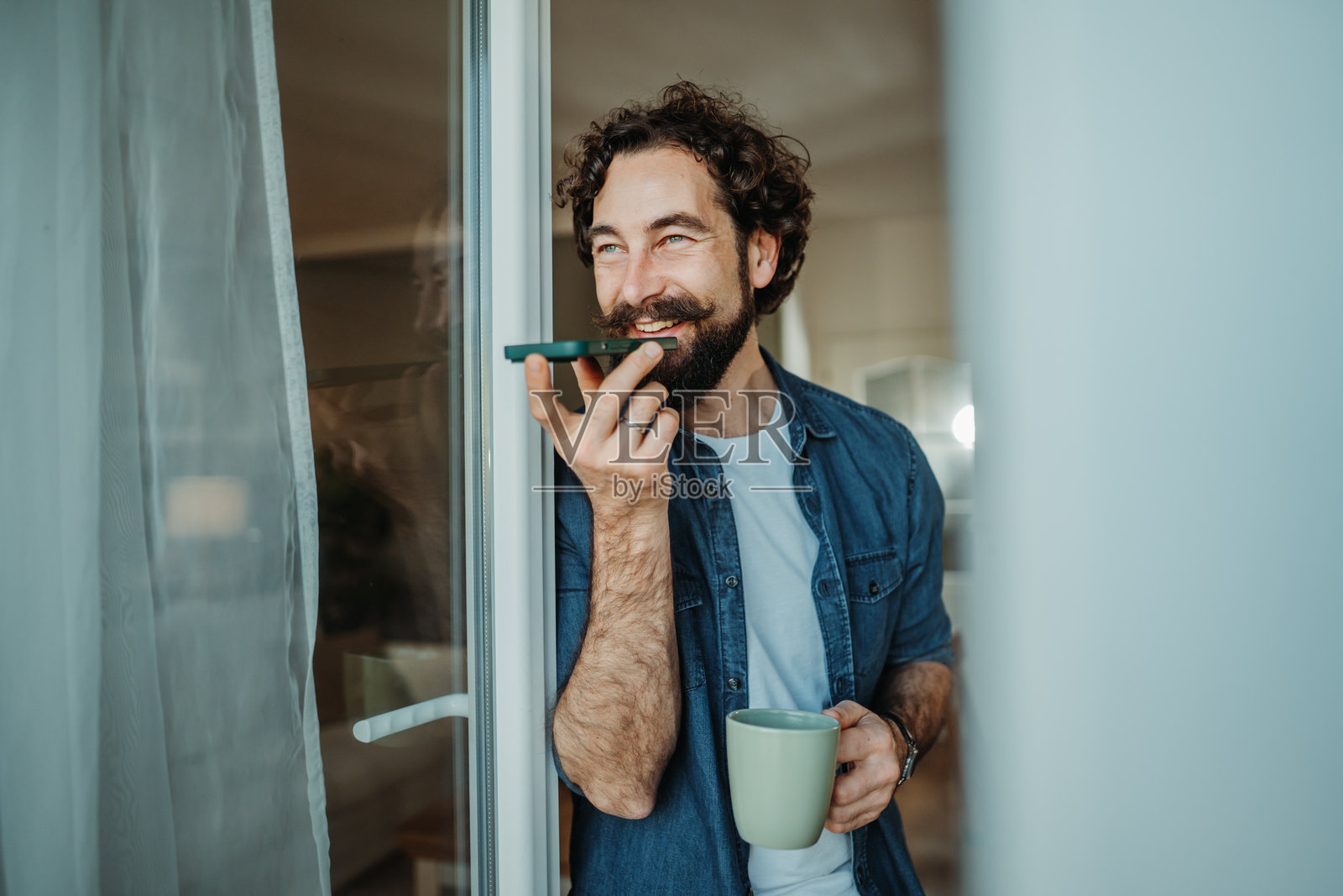 男人喝着咖啡，用智能手机发送语音消息照片摄影图片