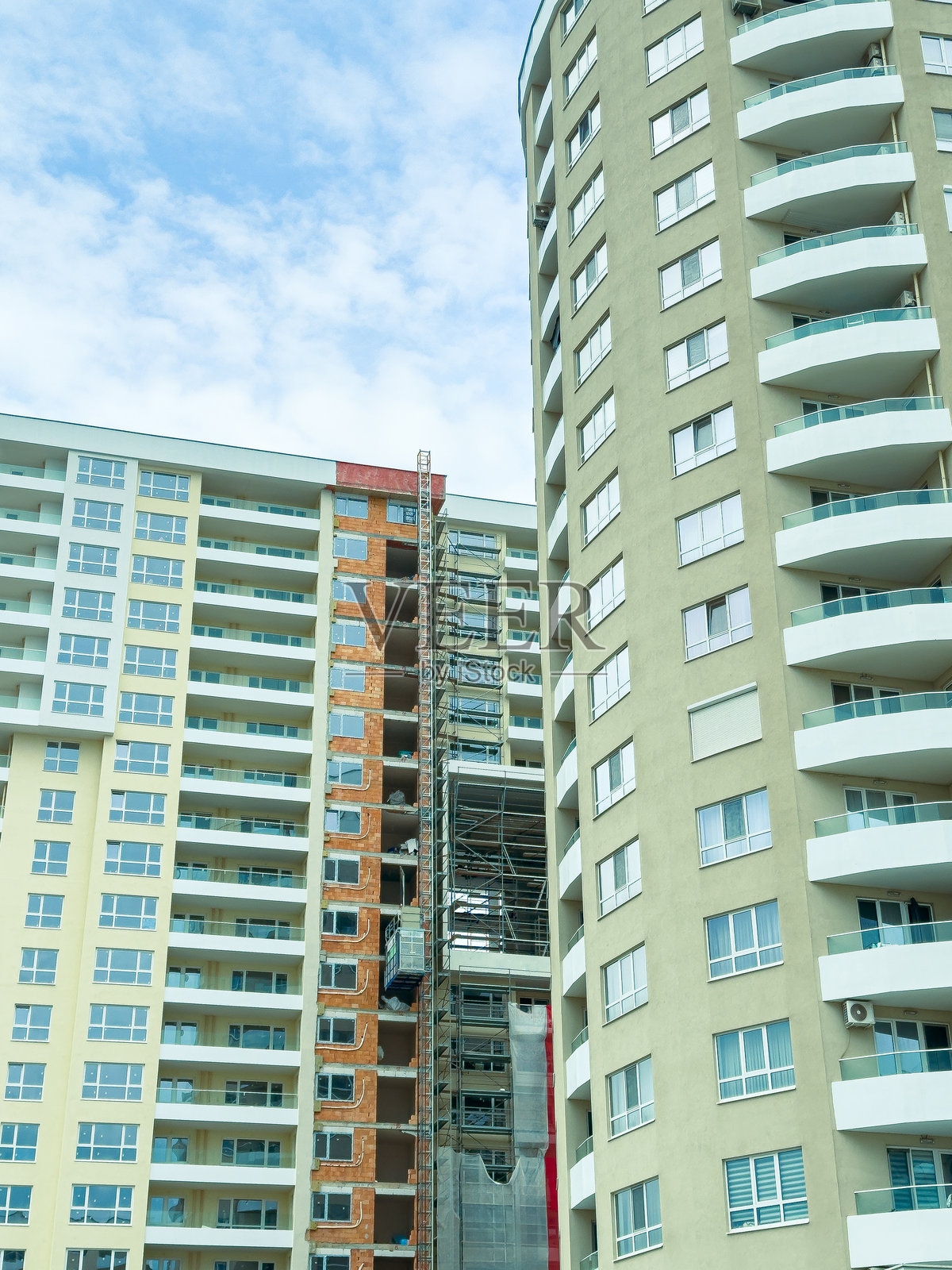 在阴天之下，一座高层建筑正在施工，旁边是一座已完工的建筑照片摄影图片