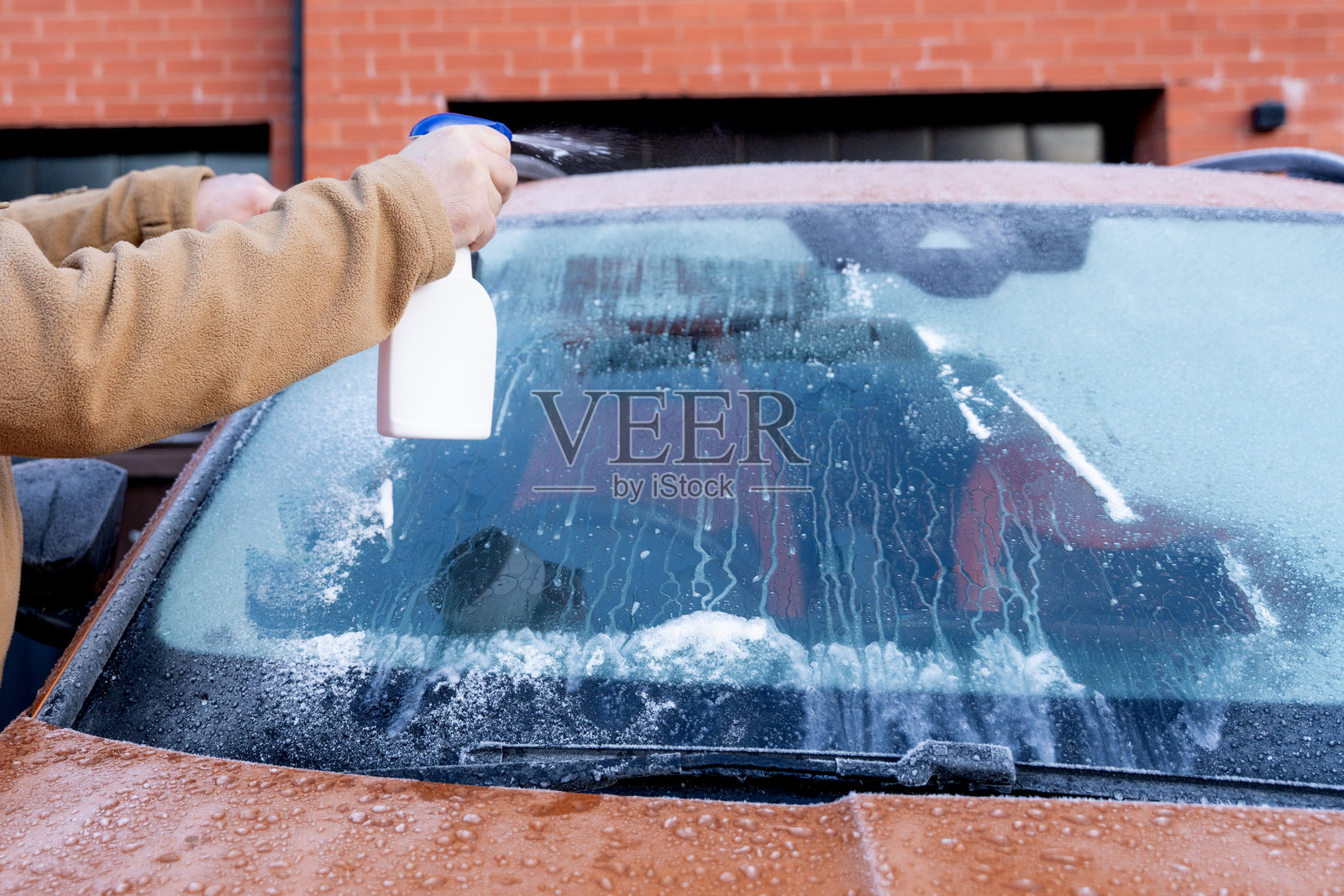 白天在住宅区用喷壶清洁汽车挡风玻璃照片摄影图片