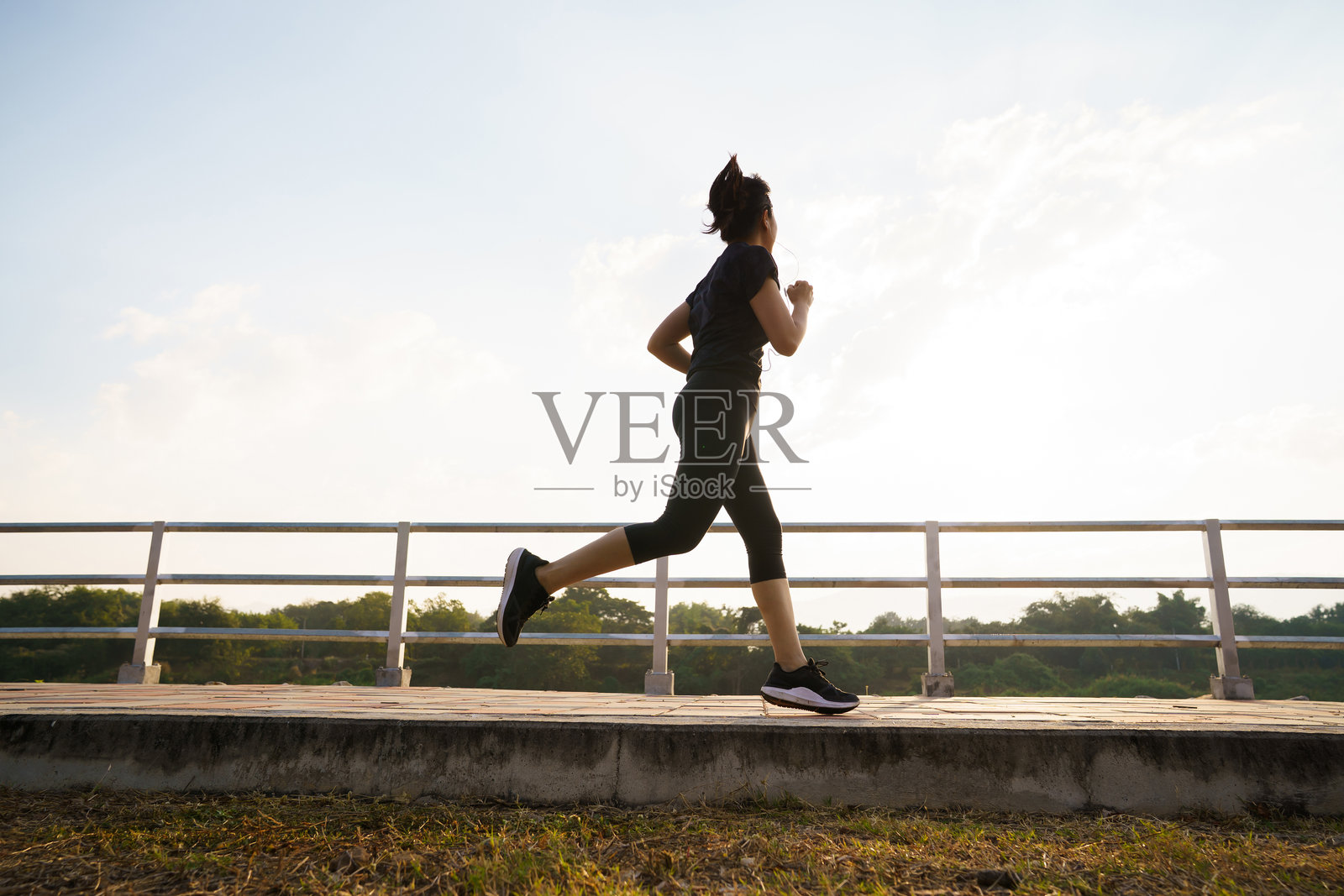 一位女士在早晨的锻炼中，在桥上慢跑照片摄影图片