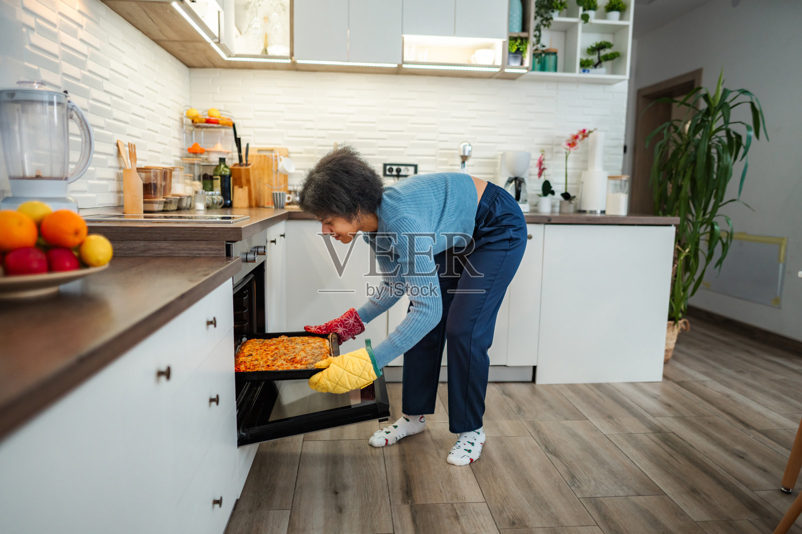 年轻女子在现代厨房烤箱中烘烤披萨照片摄影图片
