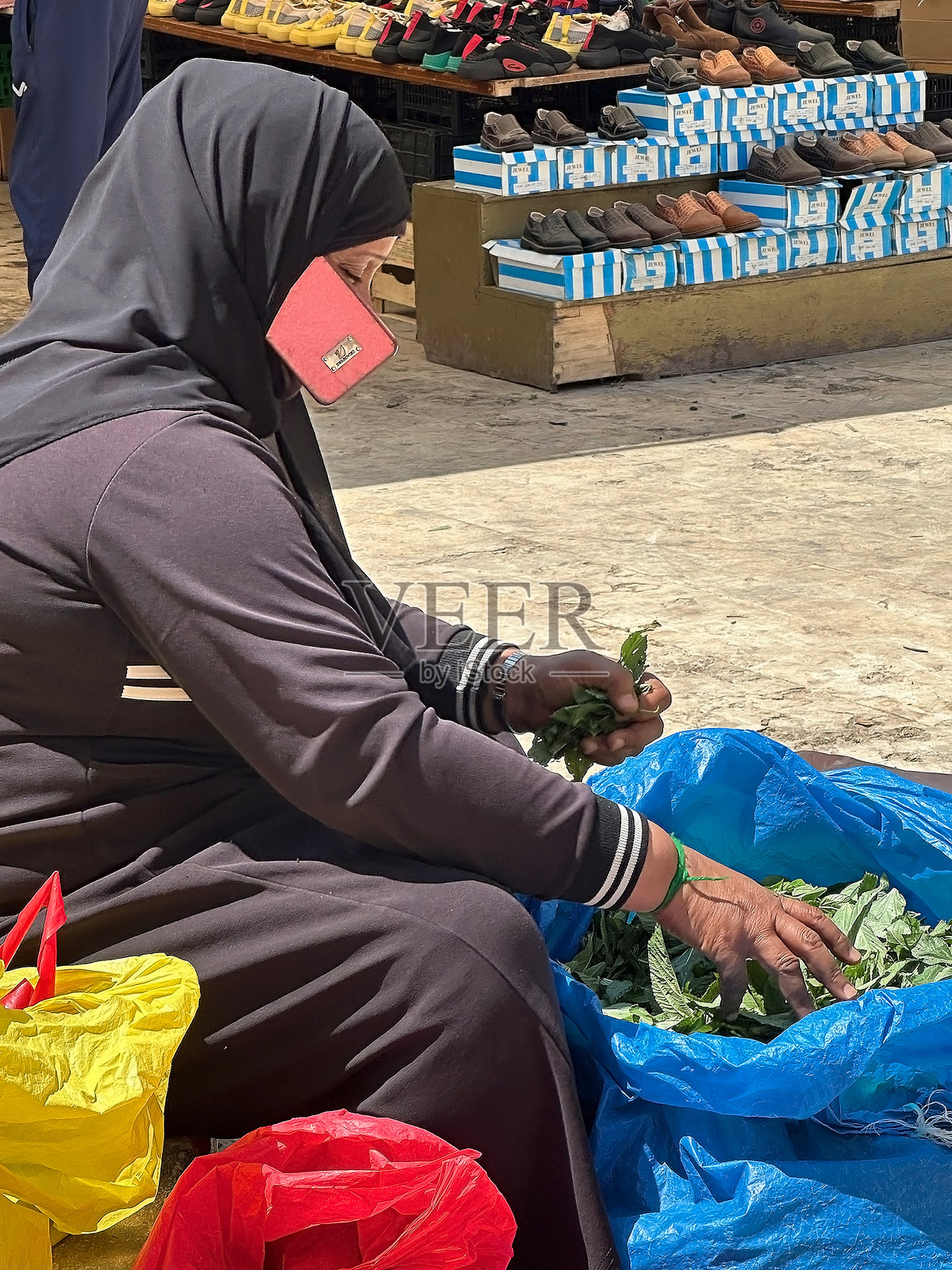 约旦妇女在约旦中西部古老的贸易城市萨尔特（Salt）的市场用手机照片摄影图片