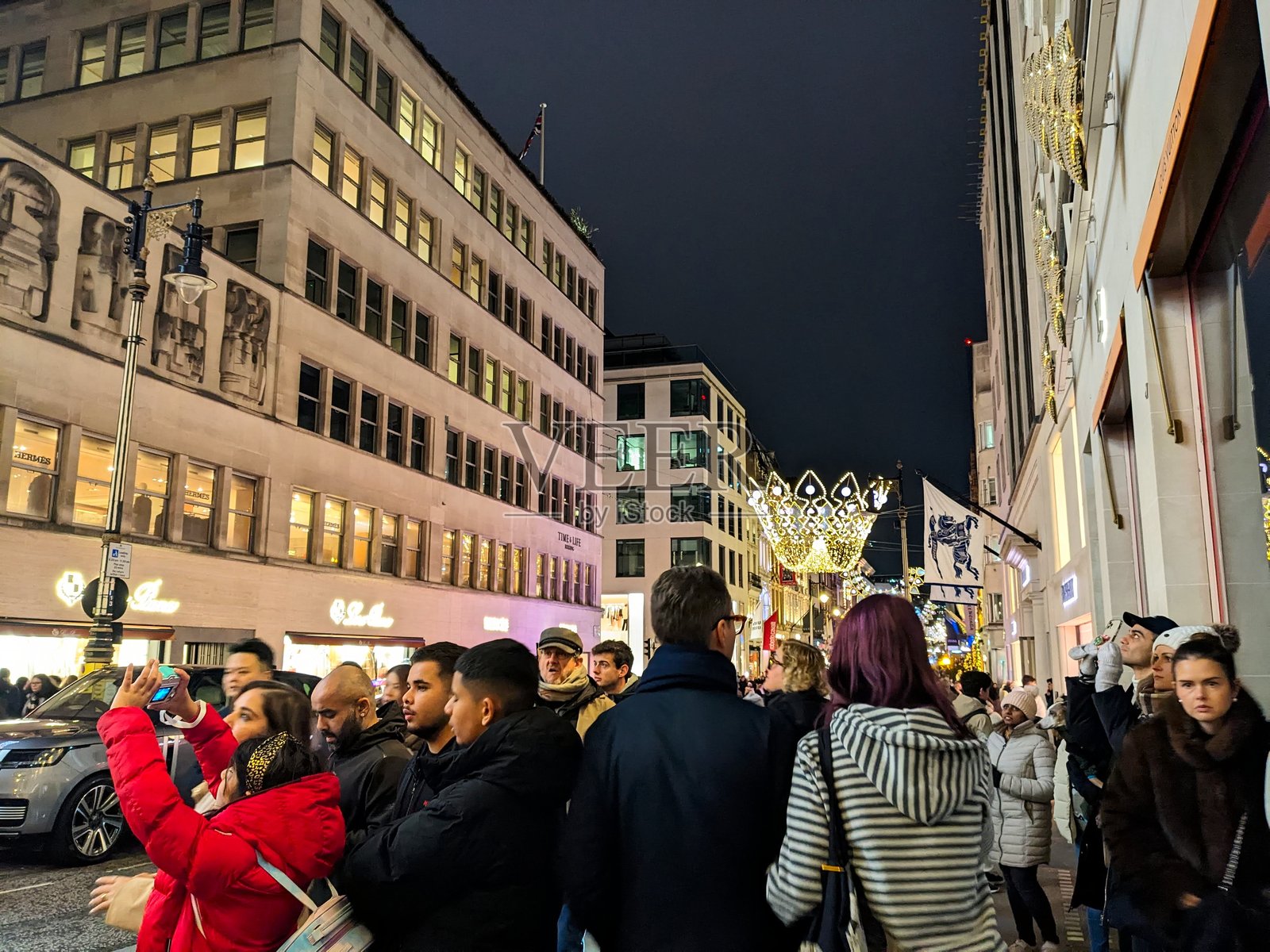 新邦德街皇冠圣诞灯饰下热闹的人群和奢侈品商店照片摄影图片