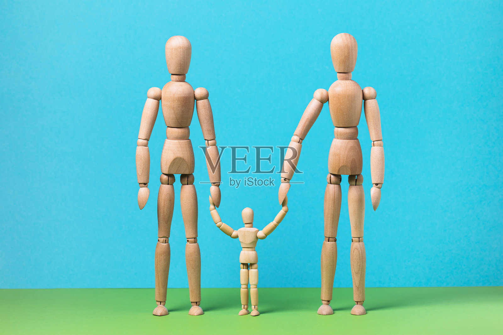 彩色背景上的木制人偶，代表家庭，包括两名成年人和一名儿童照片摄影图片