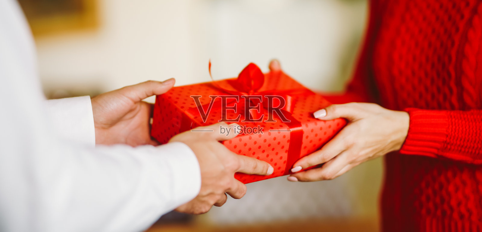 男人送给女人一个系着红色丝带的礼品盒。照片摄影图片