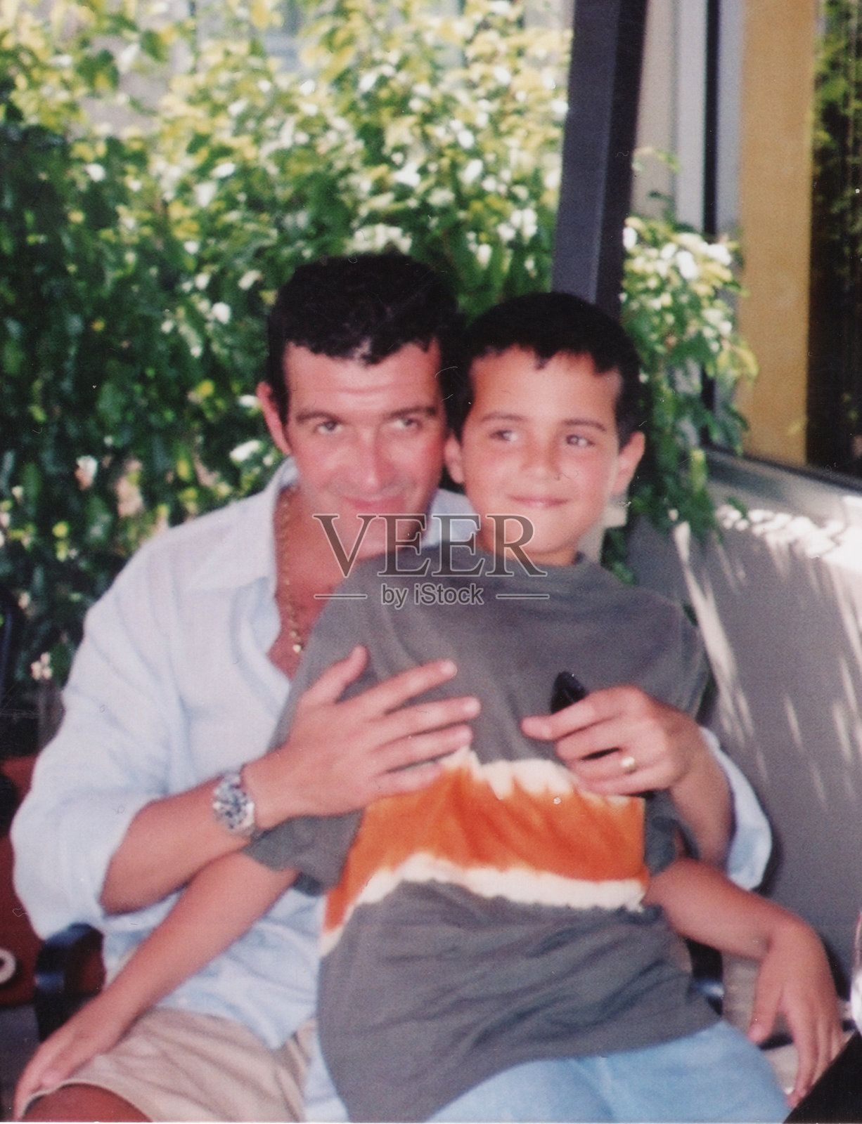 1980年代拍摄：一位面带微笑的中年男子与儿子一同看向镜头摆拍照片摄影图片