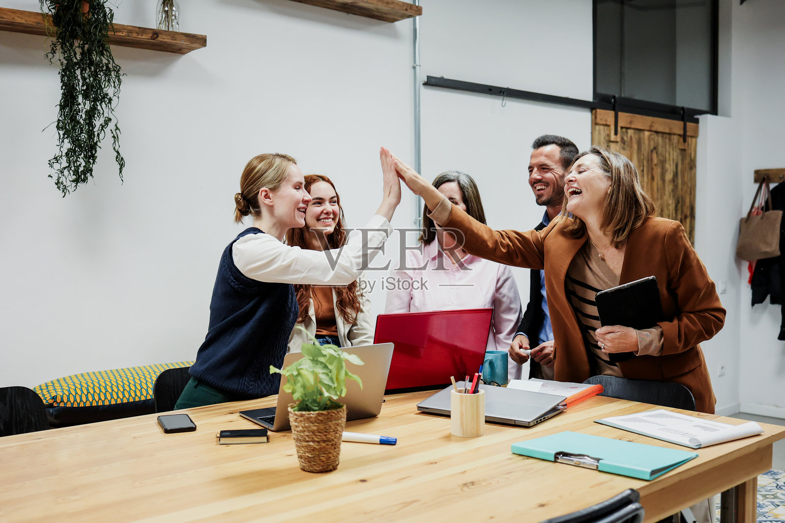 办公室里，一支由不同年龄段的西班牙裔商务团队正在一起工作并使用笔记本电脑。多元化的创业者和跨代际团队正在分享想法。照片摄影图片